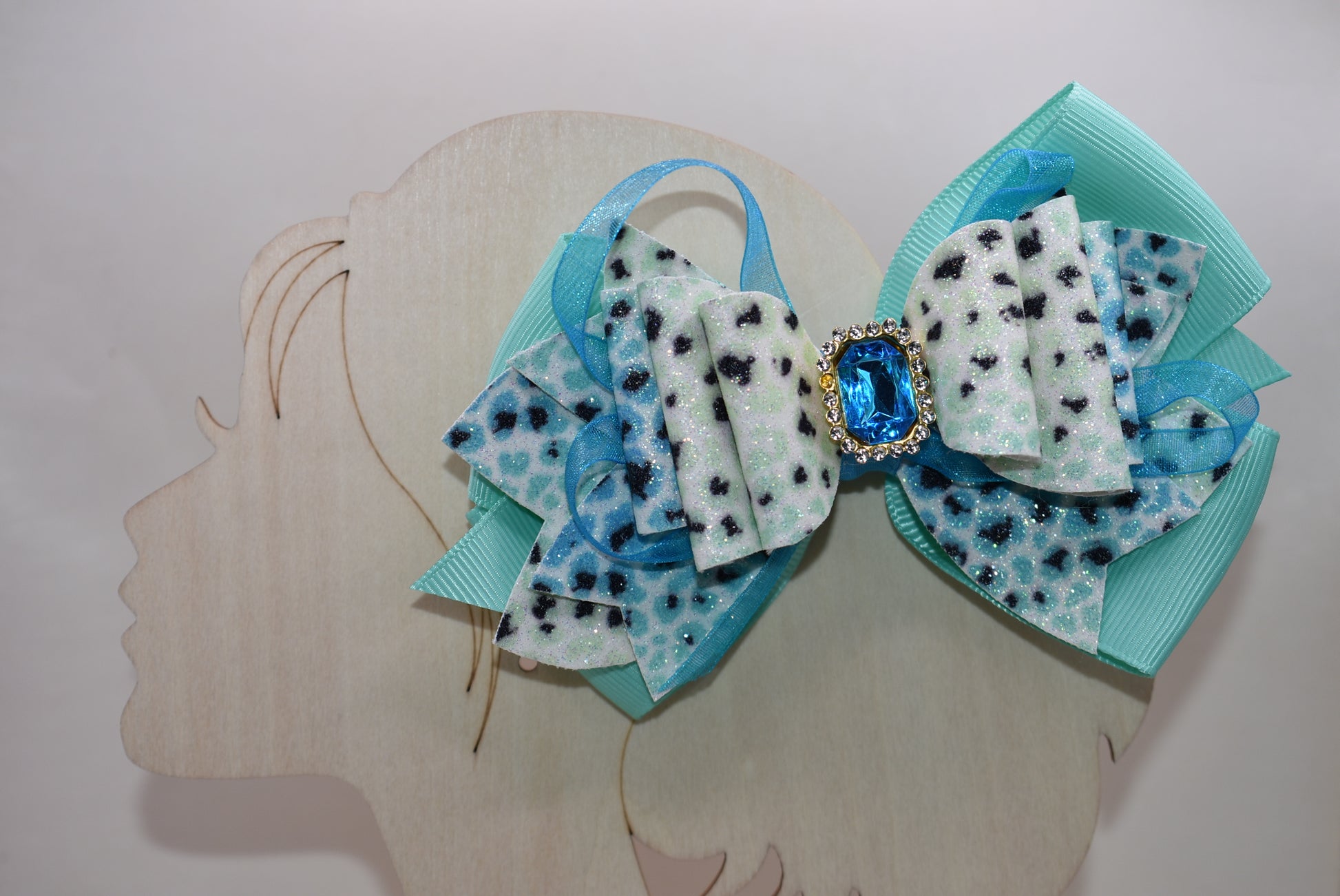 Get ready to roar! 🐆 This fabulous leopard print hair clip features multi-layered ribbon and faux leather details that bring serious style to your look. The wrapped alligator clip on back makes it super easy to secure your hair in place, while a gorgeous aqua gem sparkles on top for that perfect pop of fun. ✨ Time to unleash your wild side! 💎