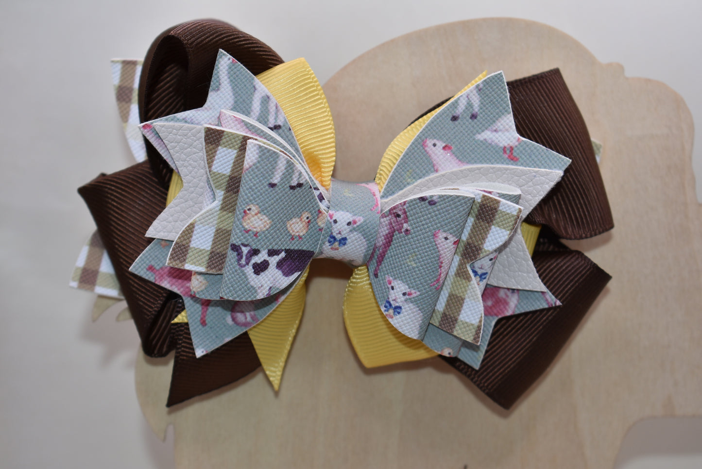 Meet the bow that'll have every farmer grinning from ear to ear! 🌾 This adorable one-of-a-kind animal-themed bow is bursting with personality, featuring layers upon layers of luxe ribbon and faux leather that create serious style depth. 🎀 Whether you're heading to the barn, a country event, or just want to add a touch of whimsy to your everyday look, this charming accessory transforms any outfit into something special. 🐄✨ Nana's Collection brings that perfect blend of cute and quirky that makes you smile
