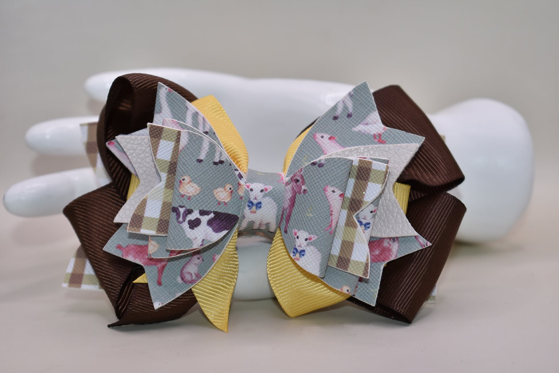 Meet the bow that'll have every farmer grinning from ear to ear! 🌾 This adorable one-of-a-kind animal-themed bow is bursting with personality, featuring layers upon layers of luxe ribbon and faux leather that create serious style depth. 🎀 Whether you're heading to the barn, a country event, or just want to add a touch of whimsy to your everyday look, this charming accessory transforms any outfit into something special. 🐄✨ Nana's Collection brings that perfect blend of cute and quirky that makes you smile