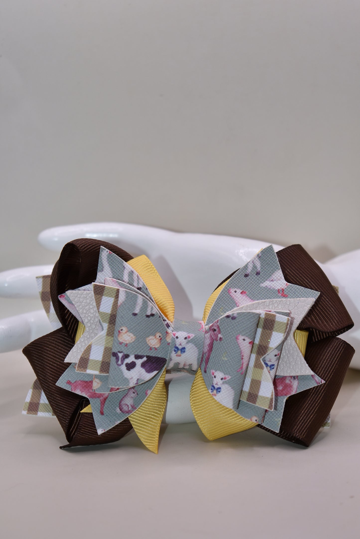 Meet the bow that'll have every farmer grinning from ear to ear! 🌾 This adorable one-of-a-kind animal-themed bow is bursting with personality, featuring layers upon layers of luxe ribbon and faux leather that create serious style depth. 🎀 Whether you're heading to the barn, a country event, or just want to add a touch of whimsy to your everyday look, this charming accessory transforms any outfit into something special. 🐄✨ Nana's Collection brings that perfect blend of cute and quirky that makes you smile