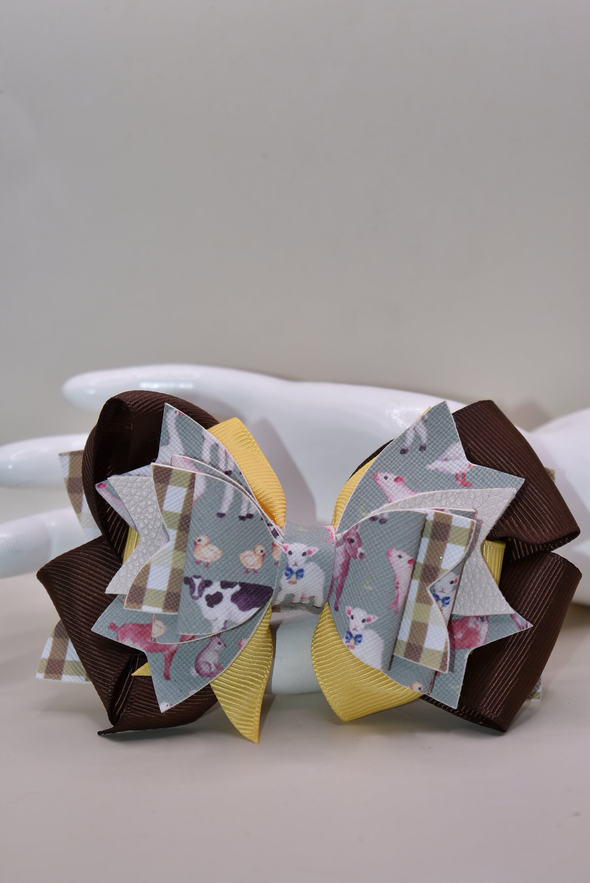 Meet the bow that'll have every farmer grinning from ear to ear! 🌾 This adorable one-of-a-kind animal-themed bow is bursting with personality, featuring layers upon layers of luxe ribbon and faux leather that create serious style depth. 🎀 Whether you're heading to the barn, a country event, or just want to add a touch of whimsy to your everyday look, this charming accessory transforms any outfit into something special. 🐄✨ Nana's Collection brings that perfect blend of cute and quirky that makes you smile