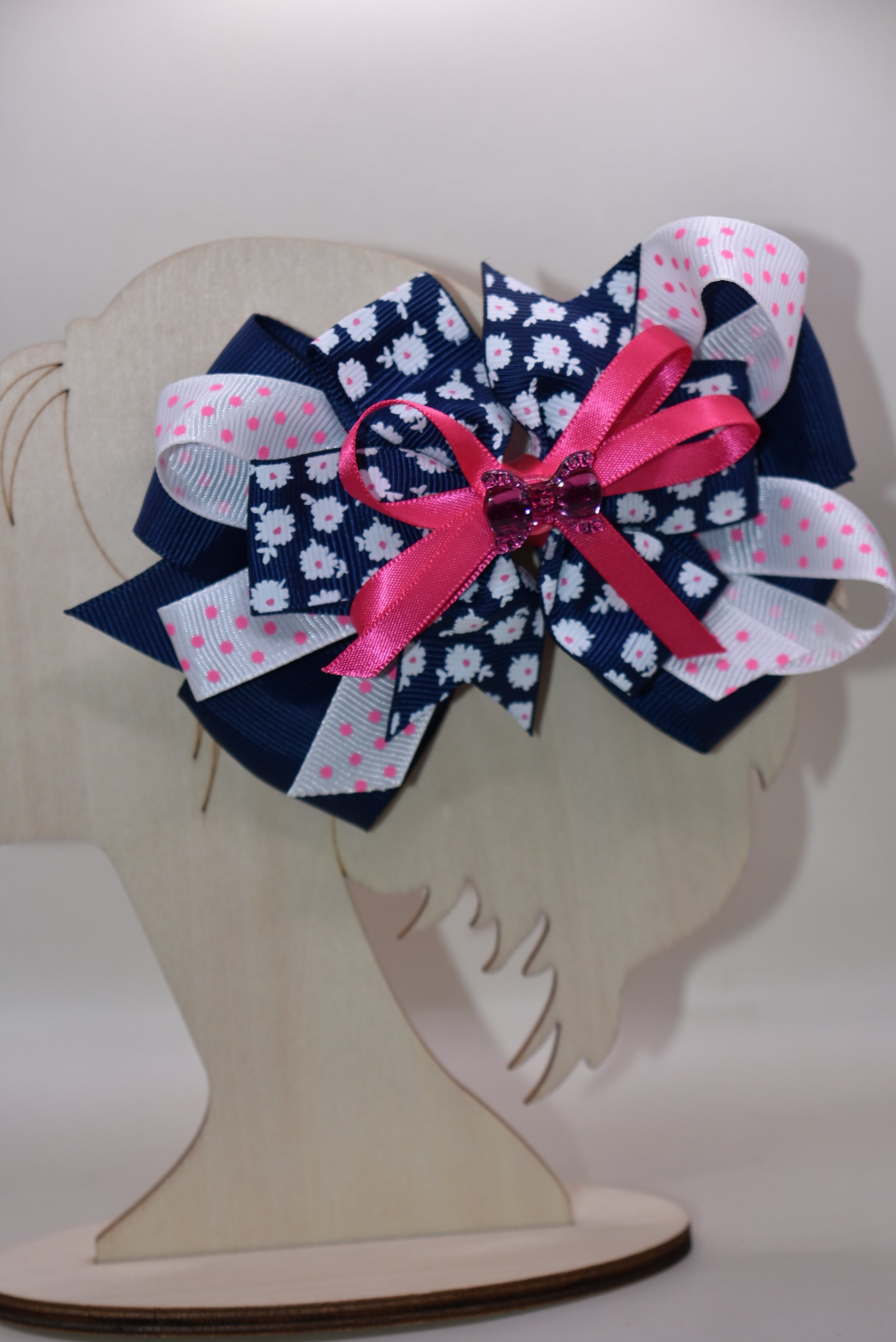 This adorable bow clip is a playful mix of navy blue and bright pink with layered textures featuring solid, floral, and polka dot patterns. 🎀 The cutest hot pink bow charm sits proudly on top, adding that extra pop of personality! ✨ Secured with a wrapped alligator clip, it stays put through all your adventures. Perfect for adding a fun, charming touch to any hairstyle! 💕