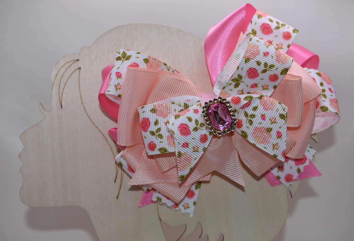 Introducing a bow that's as sweet as it is sparkly! 🌸 This charming hair clip features delicate flower motifs adorned with layers upon layers of dreamy peach and pink ribbons that dance together beautifully. A gorgeous gem sits perched on top, catching the light with every twirl and turn ✨ The wrapped alligator clip makes styling effortless—just clip and go! 💕 Perfect for adding a touch of whimsy and elegance to any hairstyle, this piece brings instant charm and personality to your look. 🎀