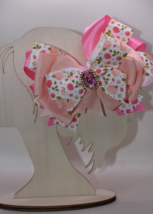 Introducing a bow that's as sweet as it is sparkly! 🌸 This charming hair clip features delicate flower motifs adorned with layers upon layers of dreamy peach and pink ribbons that dance together beautifully. A gorgeous gem sits perched on top, catching the light with every twirl and turn ✨ The wrapped alligator clip makes styling effortless—just clip and go! 💕 Perfect for adding a touch of whimsy and elegance to any hairstyle, this piece brings instant charm and personality to your look. 🎀