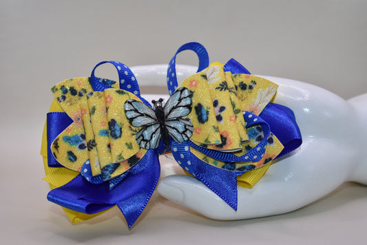 This one-of-a-kind bow brings spring vibes with vibrant layers of bright blue and yellow ribbon mixed with faux leather for texture and dimension. 🦋 A gorgeous blue butterfly charm perches perfectly on top, adding whimsical charm to any hairstyle. The alligator clip is wrapped in soft ribbon for all-day comfort, so you can wear it from morning to night without any pinching. Perfect for adding a pop of color and personality to your look! 🌈✨