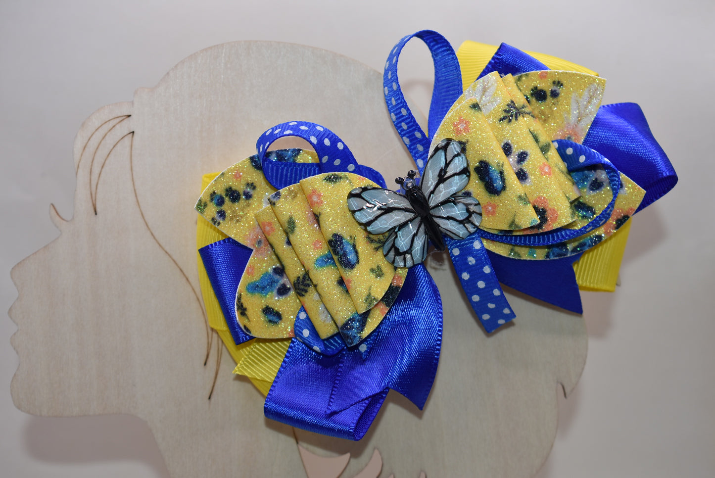 This one-of-a-kind bow brings spring vibes with vibrant layers of bright blue and yellow ribbon mixed with faux leather for texture and dimension. 🦋 A gorgeous blue butterfly charm perches perfectly on top, adding whimsical charm to any hairstyle. The alligator clip is wrapped in soft ribbon for all-day comfort, so you can wear it from morning to night without any pinching. Perfect for adding a pop of color and personality to your look! 🌈✨
