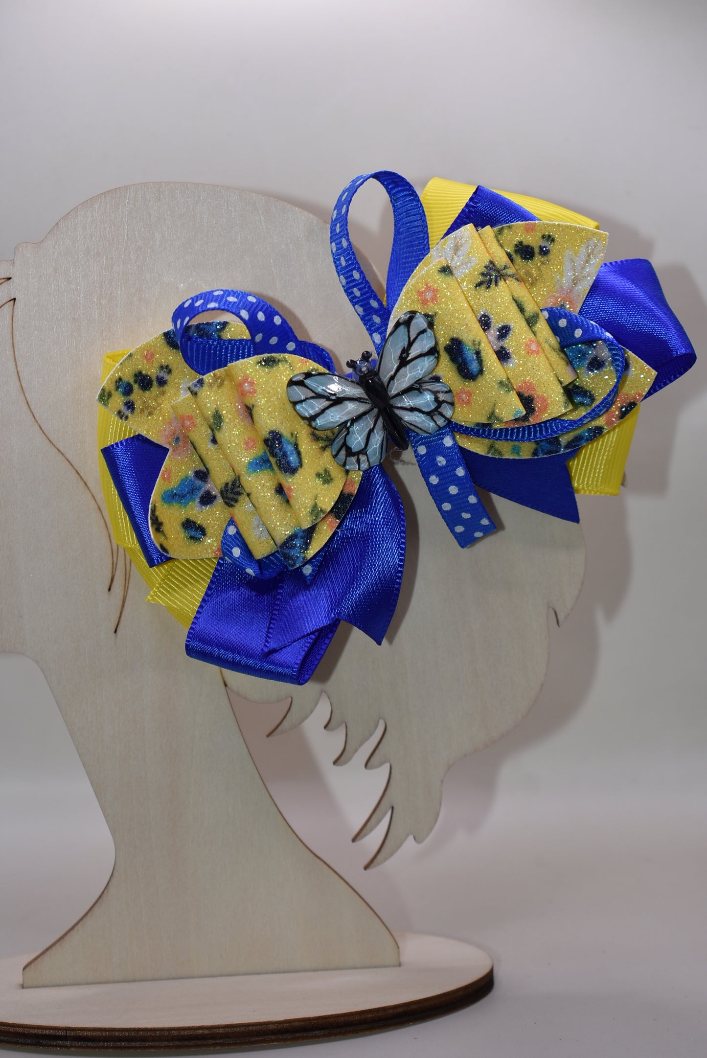 This one-of-a-kind bow brings spring vibes with vibrant layers of bright blue and yellow ribbon mixed with faux leather for texture and dimension. 🦋 A gorgeous blue butterfly charm perches perfectly on top, adding whimsical charm to any hairstyle. The alligator clip is wrapped in soft ribbon for all-day comfort, so you can wear it from morning to night without any pinching. Perfect for adding a pop of color and personality to your look! 🌈✨