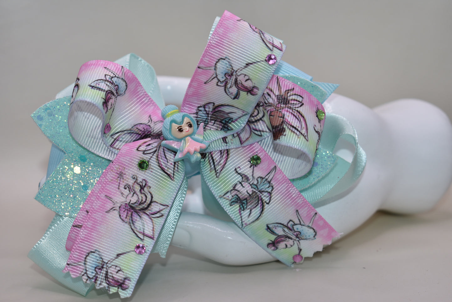 ✨ Get ready to sprinkle some magic into your day with this enchanting fairy-themed bow! Layered ribbons create gorgeous dimension, while shimmering faux leather adds extra sparkle that catches the light beautifully. Tiny gems and an adorable fairy charm bring whimsical fun to every hairstyle. The wrapped alligator clip keeps everything secure and comfortable for all-day wear. Perfect for adding a touch of fairy-tale charm to any look! 🧚♀️💎