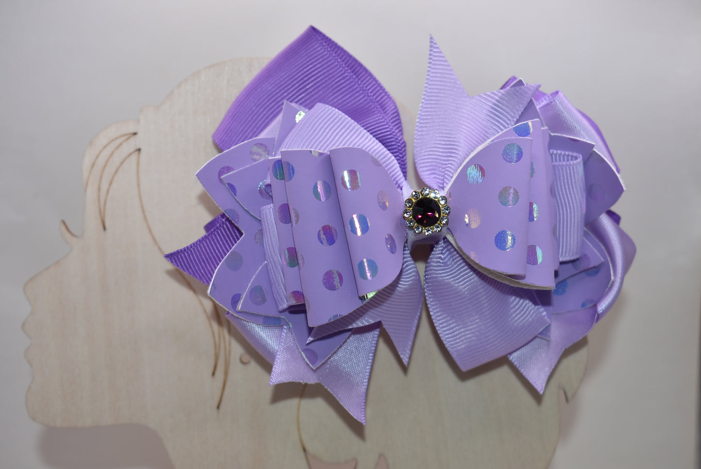 ✨ Introducing a show-stopping purple bow that's pure magic! 💜 This gorgeous accessory features a stunning lavender shade paired with luxe polka dot faux leather and cascading ribbon layers for dimensional style. A sparkling purple gem sits proudly on top, adding just the right touch of glamour and shimmer. ✨ Secured with a wrapped alligator clip for a secure, comfortable hold all day long. Perfect for adding a playful pop of color to any look! 🎀