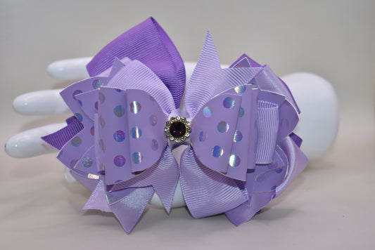 ✨ Introducing a show-stopping purple bow that's pure magic! 💜 This gorgeous accessory features a stunning lavender shade paired with luxe polka dot faux leather and cascading ribbon layers for dimensional style. A sparkling purple gem sits proudly on top, adding just the right touch of glamour and shimmer. ✨ Secured with a wrapped alligator clip for a secure, comfortable hold all day long. Perfect for adding a playful pop of color to any look! 🎀