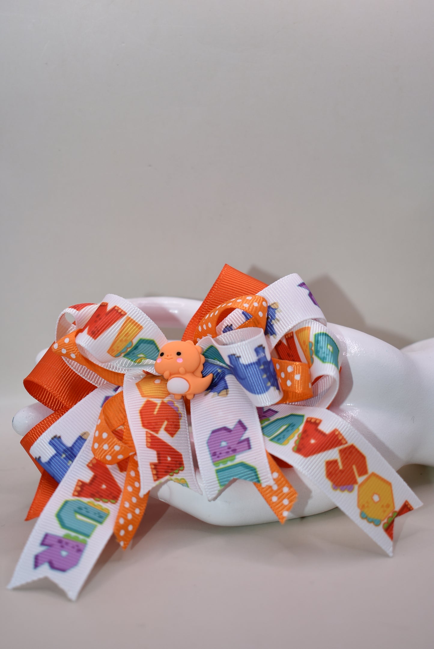 Meet your new favorite hair accessory! 🦕✨ This adorable orange dinosaur perches happily atop layers of vibrant ribbon, bringing instant joy to any hairstyle. The playful design features a wrapped alligator clip that's super easy to use—just clip and go! Perfect for adding a pop of personality and cuteness to your day. Whether you're heading to school, a playdate, or just want to smile a little brighter, this charming dino bow is ready to make your look roar with fun! 🎀😊