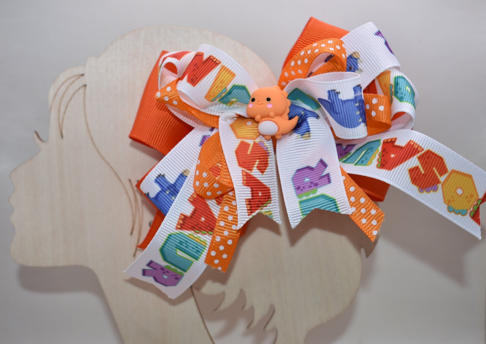 Meet your new favorite hair accessory! 🦕✨ This adorable orange dinosaur perches happily atop layers of vibrant ribbon, bringing instant joy to any hairstyle. The playful design features a wrapped alligator clip that's super easy to use—just clip and go! Perfect for adding a pop of personality and cuteness to your day. Whether you're heading to school, a playdate, or just want to smile a little brighter, this charming dino bow is ready to make your look roar with fun! 🎀😊