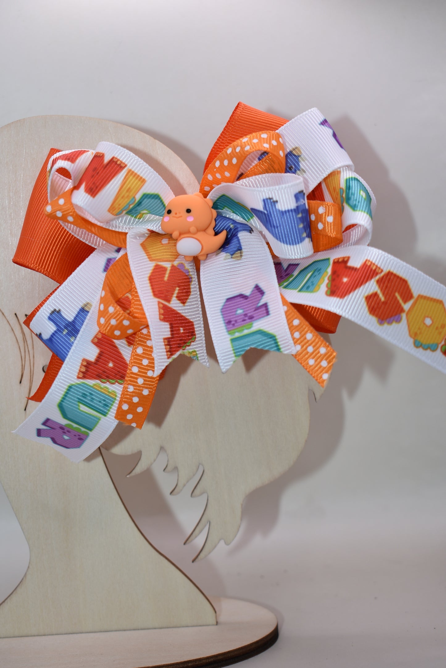 Meet your new favorite hair accessory! 🦕✨ This adorable orange dinosaur perches happily atop layers of vibrant ribbon, bringing instant joy to any hairstyle. The playful design features a wrapped alligator clip that's super easy to use—just clip and go! Perfect for adding a pop of personality and cuteness to your day. Whether you're heading to school, a playdate, or just want to smile a little brighter, this charming dino bow is ready to make your look roar with fun! 🎀😊