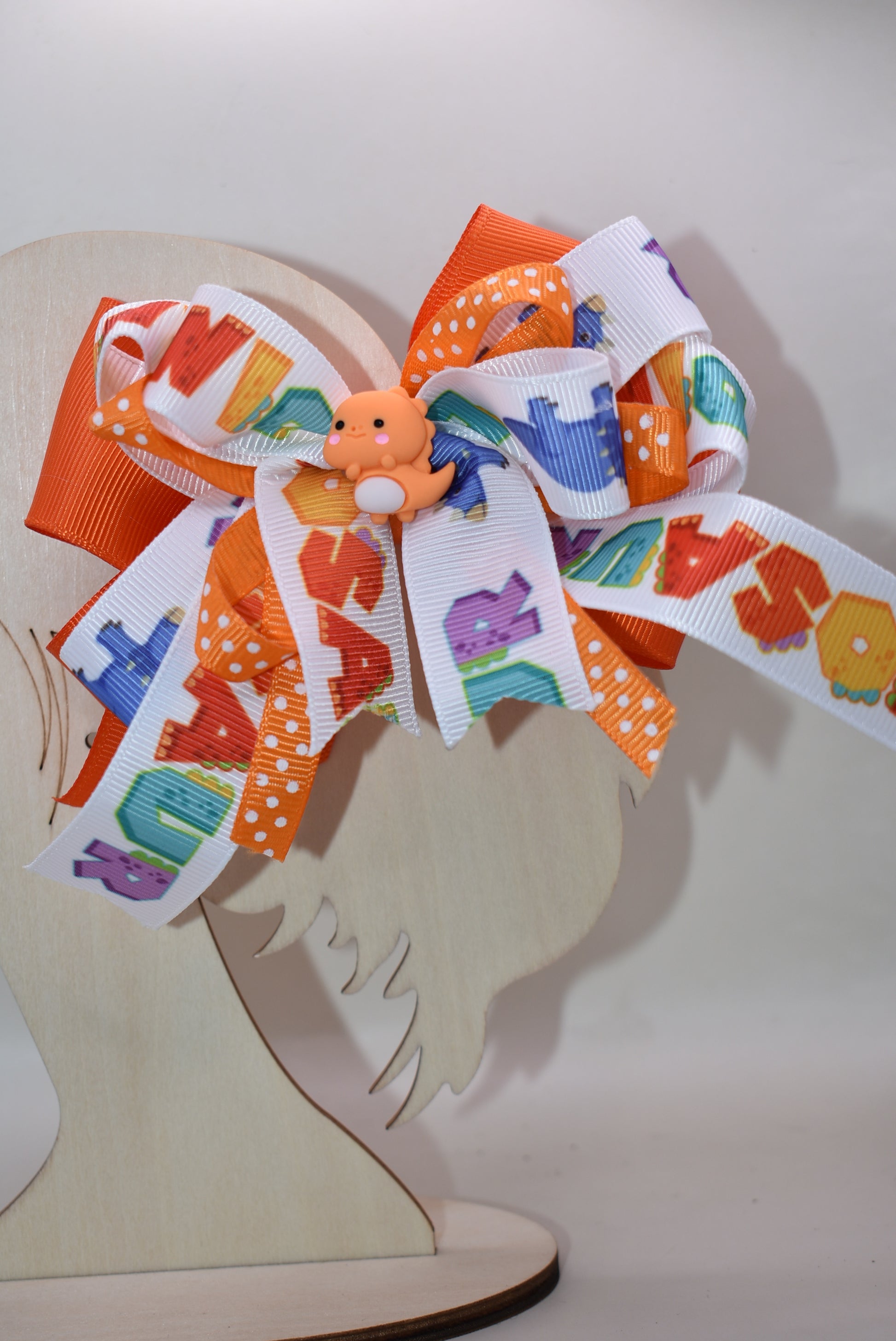 Meet your new favorite hair accessory! 🦕✨ This adorable orange dinosaur perches happily atop layers of vibrant ribbon, bringing instant joy to any hairstyle. The playful design features a wrapped alligator clip that's super easy to use—just clip and go! Perfect for adding a pop of personality and cuteness to your day. Whether you're heading to school, a playdate, or just want to smile a little brighter, this charming dino bow is ready to make your look roar with fun! 🎀😊