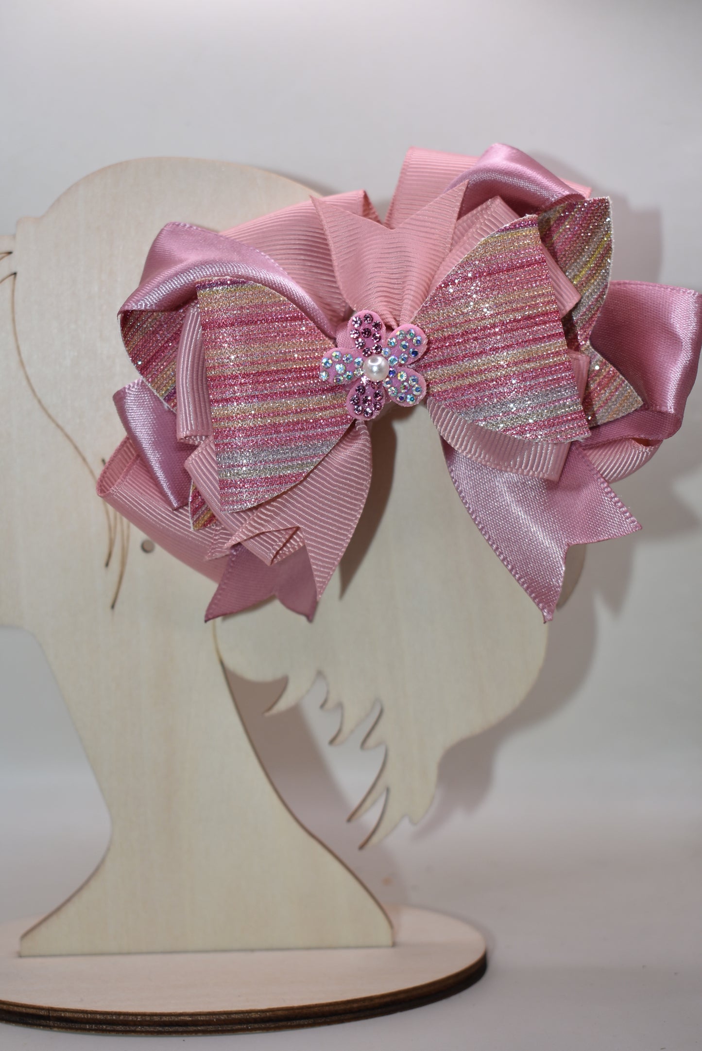 ✨ Introducing a dazzling accessory that brings instant glamour to any hairstyle! This beauty features shimmering glitter faux leather blended with luxe satin and grosgrain ribbon for a multi-textured look that catches the light beautifully. 💎 Topped with an adorable sparkly flower and delicate pearl detail, it's the perfect finishing touch for special occasions or everyday sparkle. The convenient wrapped alligator clip makes it effortless to secure and wear all day long. 🌸 Pure magic for your hair!