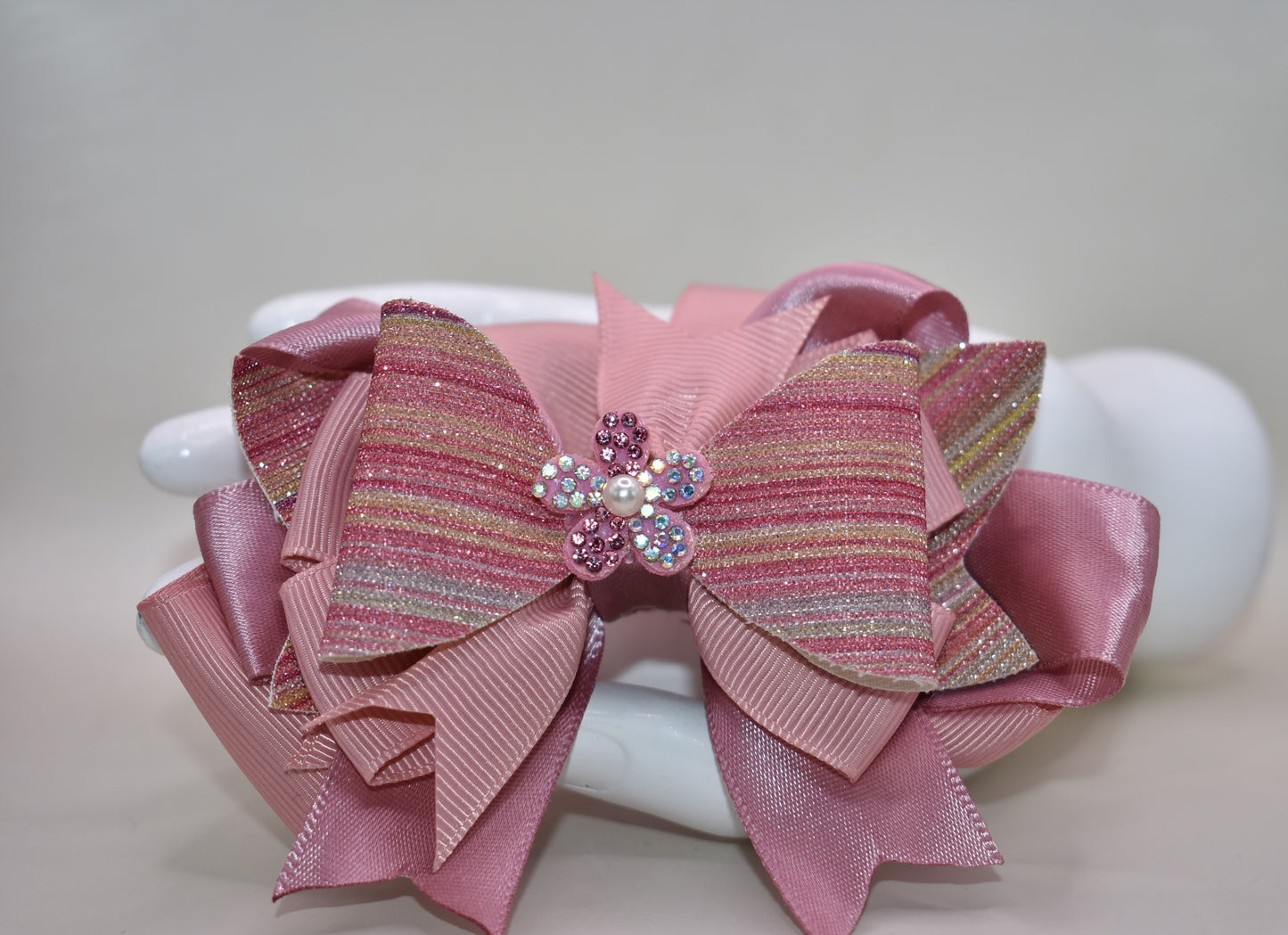 ✨ Introducing a dazzling accessory that brings instant glamour to any hairstyle! This beauty features shimmering glitter faux leather blended with luxe satin and grosgrain ribbon for a multi-textured look that catches the light beautifully. 💎 Topped with an adorable sparkly flower and delicate pearl detail, it's the perfect finishing touch for special occasions or everyday sparkle. The convenient wrapped alligator clip makes it effortless to secure and wear all day long. 🌸 Pure magic for your hair!