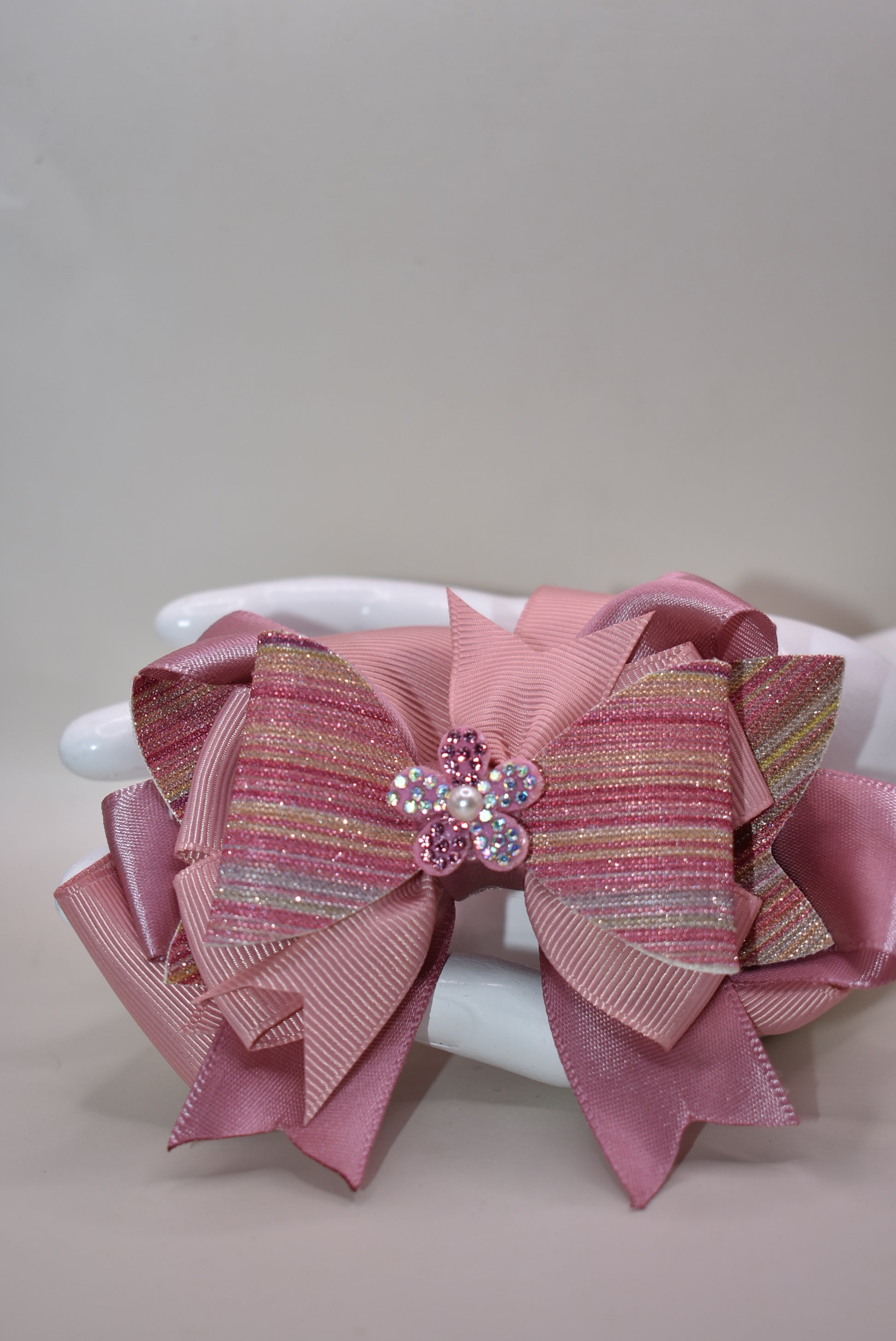 ✨ Introducing a dazzling accessory that brings instant glamour to any hairstyle! This beauty features shimmering glitter faux leather blended with luxe satin and grosgrain ribbon for a multi-textured look that catches the light beautifully. 💎 Topped with an adorable sparkly flower and delicate pearl detail, it's the perfect finishing touch for special occasions or everyday sparkle. The convenient wrapped alligator clip makes it effortless to secure and wear all day long. 🌸 Pure magic for your hair!