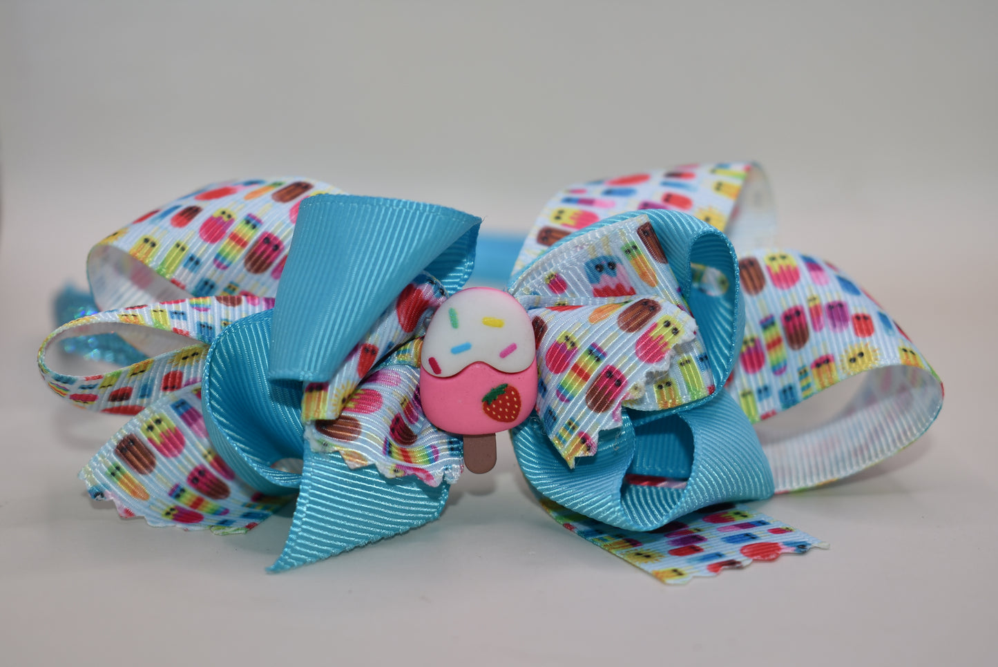 Wrap your hair in sweetness with this delightful satin headband! 🎀 Featuring a soft, flexible design that stays comfortable all day long, this charming piece showcases a playful ice cream cone charm perched on top and a bow adorned with layers of fun, glittery ribbon. 🍦✨ Perfect for ice cream lovers and fashion enthusiasts alike, it's the ideal accessory to add a whimsical touch to any outfit. Whether you're heading out for a treat or just want to spread some joy, this headband brings instant personality 