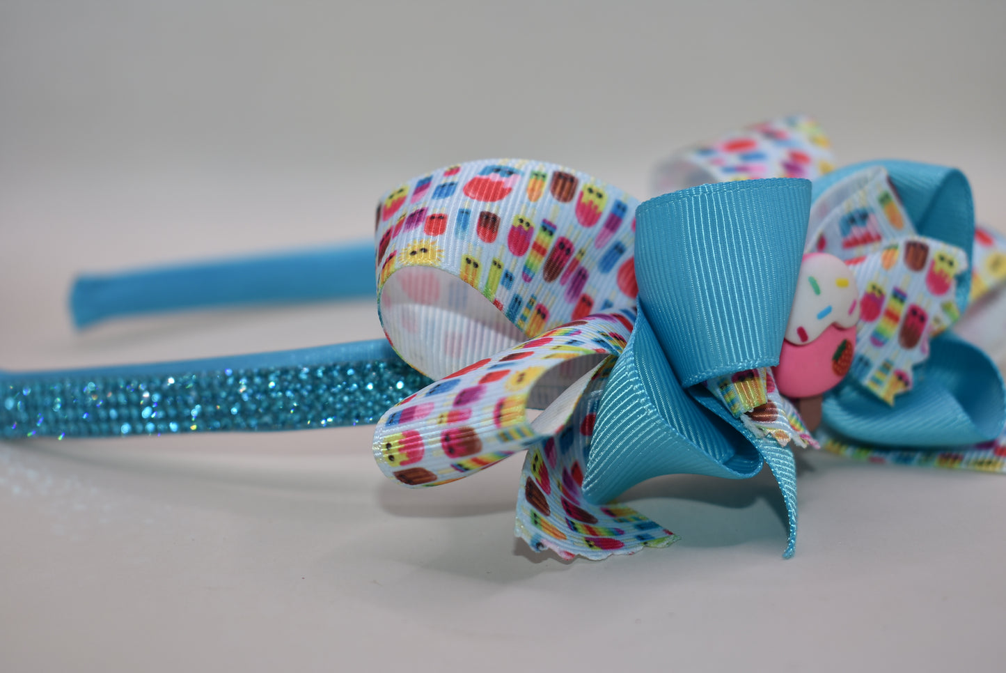 Wrap your hair in sweetness with this delightful satin headband! 🎀 Featuring a soft, flexible design that stays comfortable all day long, this charming piece showcases a playful ice cream cone charm perched on top and a bow adorned with layers of fun, glittery ribbon. 🍦✨ Perfect for ice cream lovers and fashion enthusiasts alike, it's the ideal accessory to add a whimsical touch to any outfit. Whether you're heading out for a treat or just want to spread some joy, this headband brings instant personality 