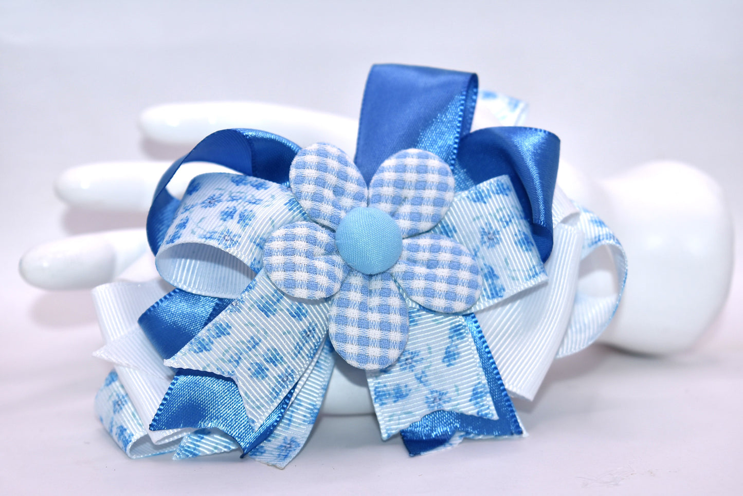 Welcome to spring with this charming blue bow! 🌸 This delightful accessory features a pretty blue floral ribbon beautifully mixed with coordinating blue and white ribbon, topped with an adorable checkered flower detail. 🎀 The wrapped alligator clip on the back makes it super easy to pop on and off whenever you need a fresh, springy touch. Perfect for adding a pop of color to any hairstyle! 💙✨