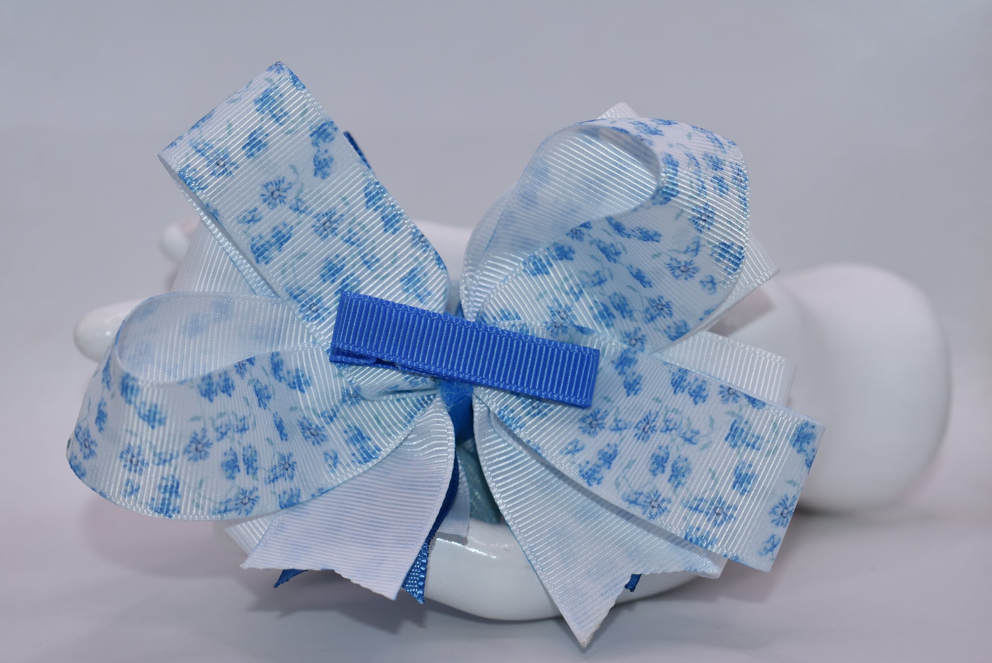 Welcome to spring with this charming blue bow! 🌸 This delightful accessory features a pretty blue floral ribbon beautifully mixed with coordinating blue and white ribbon, topped with an adorable checkered flower detail. 🎀 The wrapped alligator clip on the back makes it super easy to pop on and off whenever you need a fresh, springy touch. Perfect for adding a pop of color to any hairstyle! 💙✨
