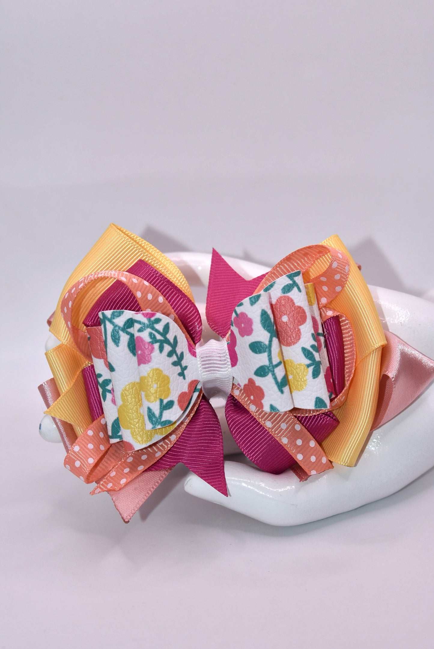 Get ready to turn heads with this adorable floral bow! 🌸 Bursting with pretty hues of orange, pink, and yellow, this charming accessory features delicate flowers, playful polka dots, and layers upon layers of ribbon for maximum cuteness. 🎀 The secure wrapped alligator clip keeps your style in place all day long. Perfect for adding a pop of color and personality to any look—you'll absolutely fall in love! 💕✨