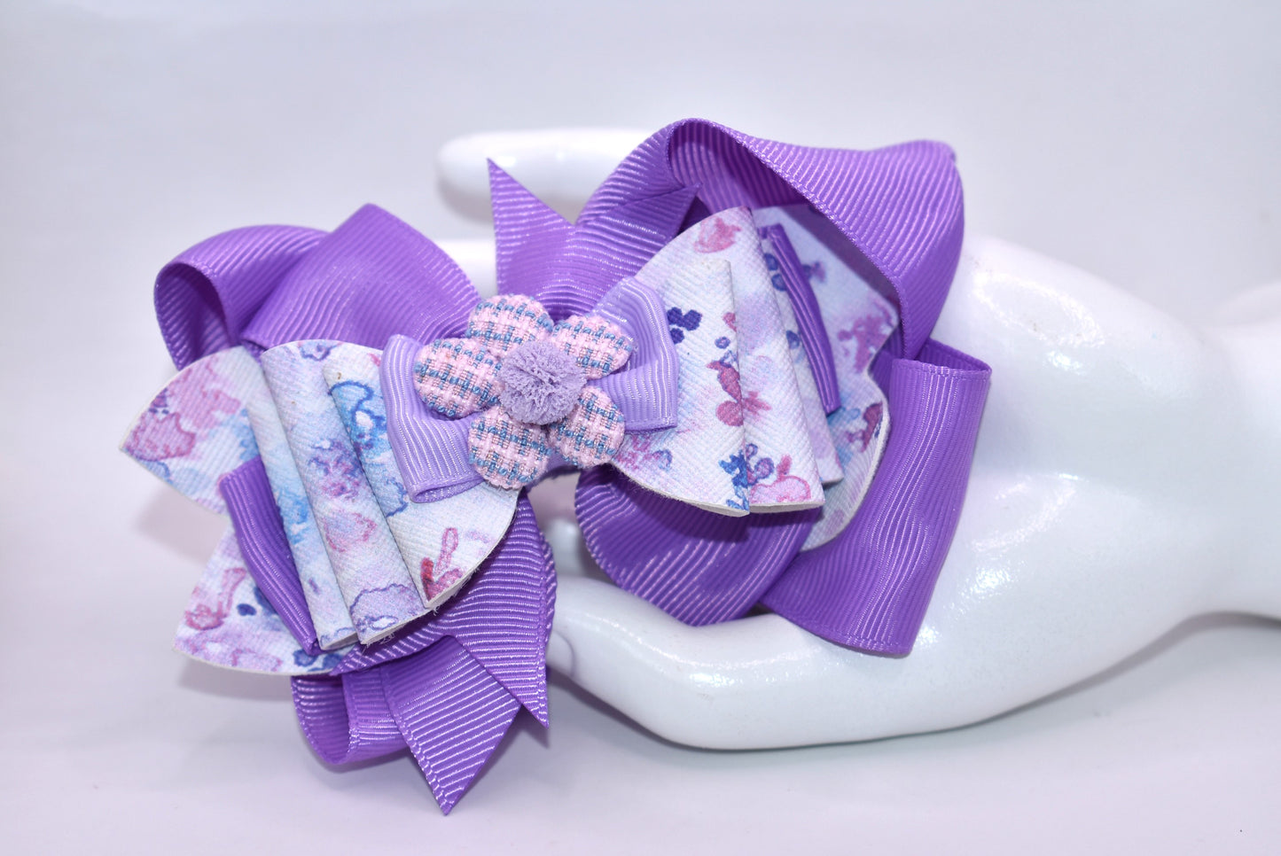 Elevate your bow game with this charming purple creation! 💜 Featuring a delightful floral design layered with rich purple ribbons, this bow brings instant personality to any hairstyle. The adorable purple flower topped with a fluffy pom pom adds that extra touch of whimsy. ✨ Wrapped in a secure alligator clip, it stays put all day long, so you can play, explore, and have fun without worry. Perfect for spring adventures! 🌸