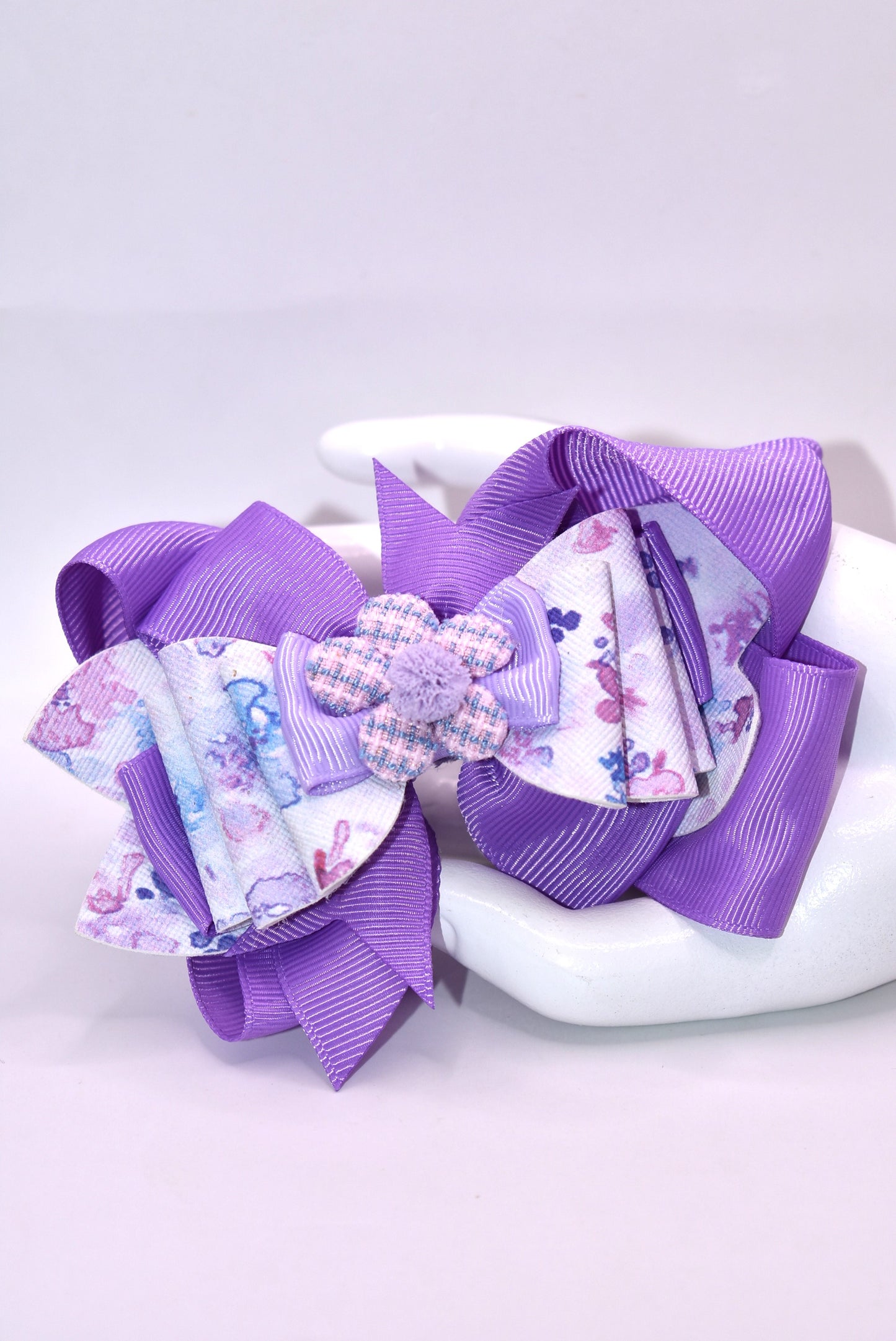 Elevate your bow game with this charming purple creation! 💜 Featuring a delightful floral design layered with rich purple ribbons, this bow brings instant personality to any hairstyle. The adorable purple flower topped with a fluffy pom pom adds that extra touch of whimsy. ✨ Wrapped in a secure alligator clip, it stays put all day long, so you can play, explore, and have fun without worry. Perfect for spring adventures! 🌸