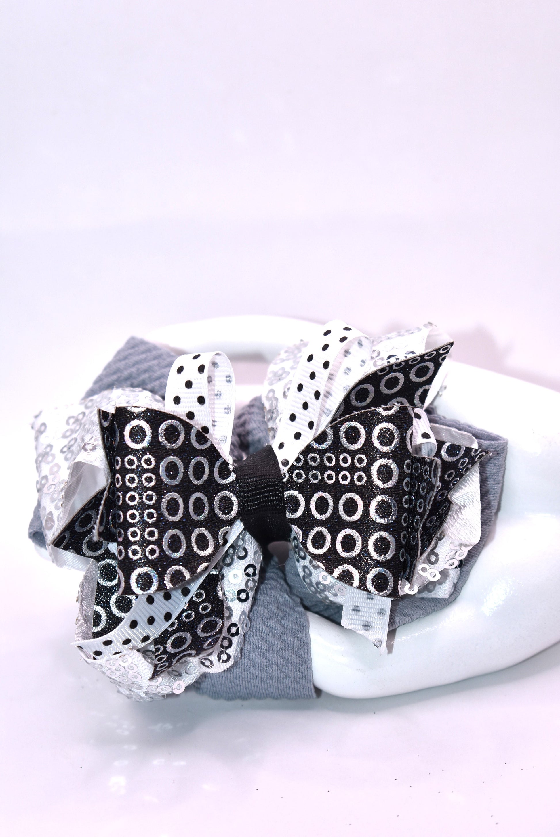 ✨ Stand out with Nana's Collection A4 – the bow that breaks the mold! 🎀 This stunning piece features a chic black, white, and silver palette that works together like magic. ✨ Packed with eye-catching shapes and sparkles that catch every light, it's the perfect accessory for anyone who dares to be different. 💫 The wrapped alligator clip slides on effortlessly, so you can rock this beauty all day long without a second thought. 🌟