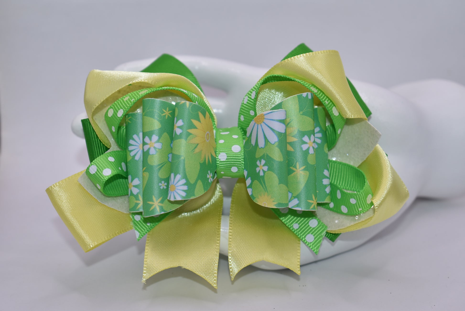 Brighten your style with this cheerful spring bow! 🌻 Bursting with vibrant green and yellow hues, it showcases a delightful blend of flower motifs and playful polka dots. The eye-catching design comes to life through layered ribbons and faux leather textures that add depth and movement. Secured with a wrapped alligator clip, it's ready to wear whenever inspiration strikes. 🎀 Your wardrobe just got a whole lot more fun! ✨💛