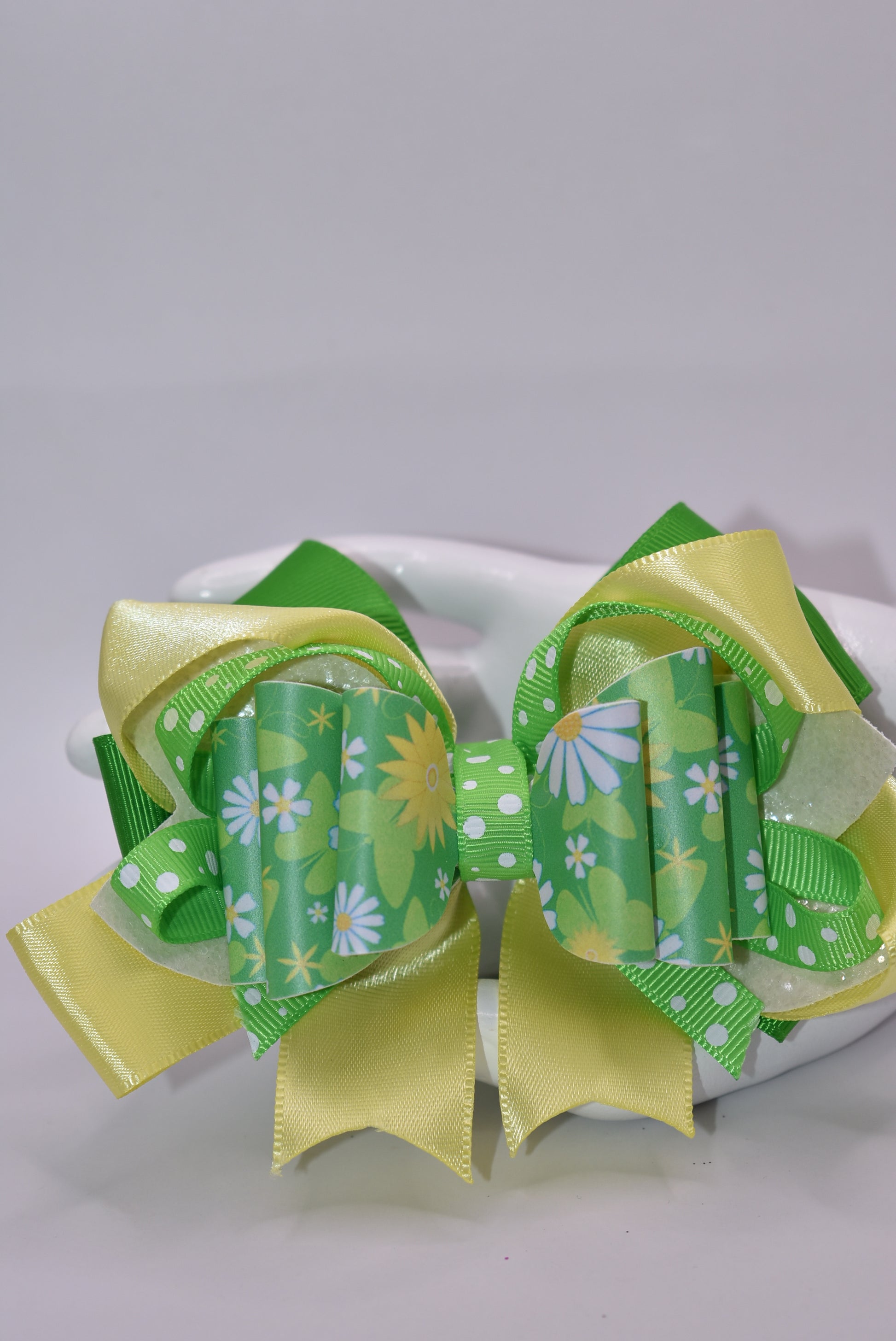 Brighten your style with this cheerful spring bow! 🌻 Bursting with vibrant green and yellow hues, it showcases a delightful blend of flower motifs and playful polka dots. The eye-catching design comes to life through layered ribbons and faux leather textures that add depth and movement. Secured with a wrapped alligator clip, it's ready to wear whenever inspiration strikes. 🎀 Your wardrobe just got a whole lot more fun! ✨💛