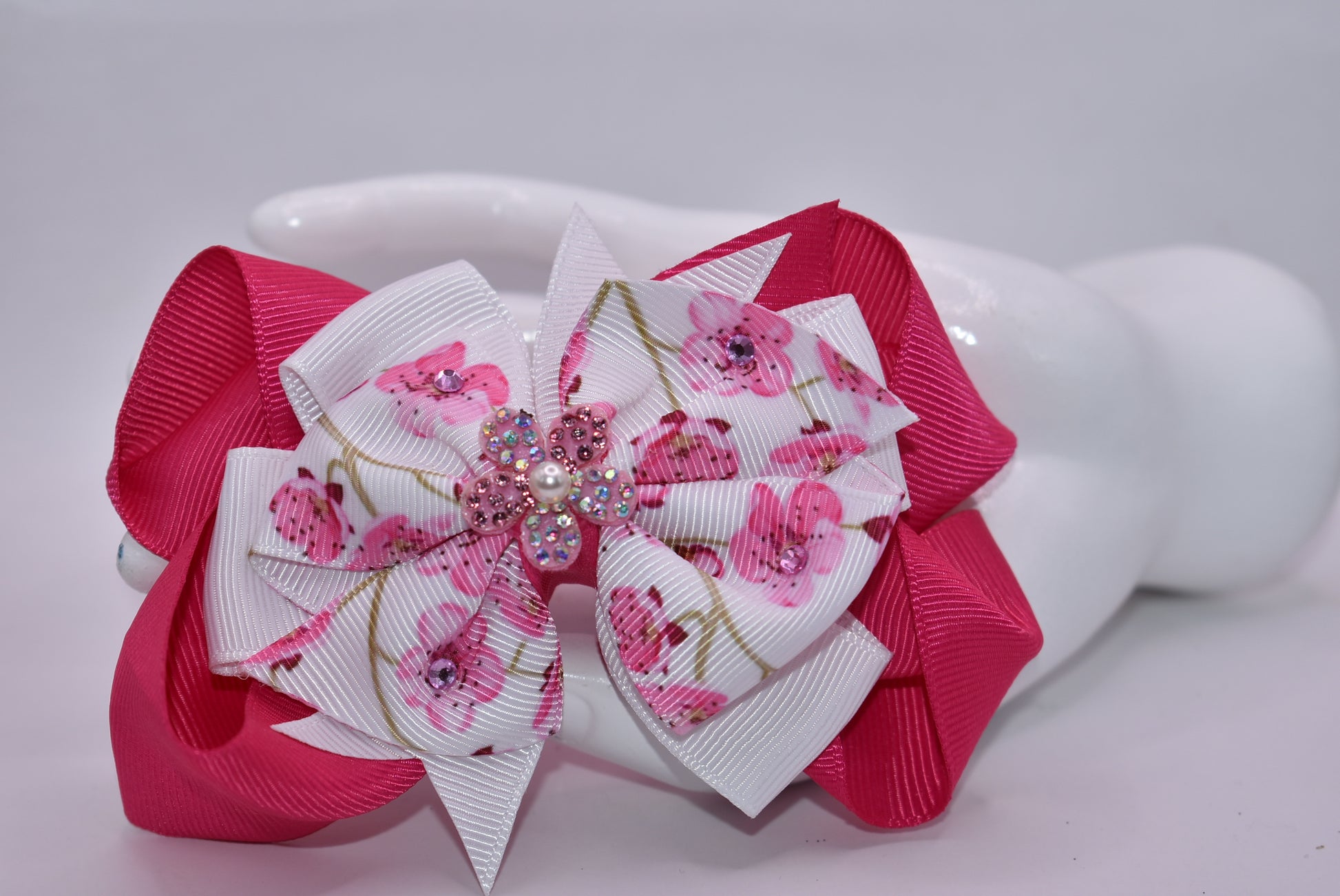 Add a pop of sparkle to your spring style with this vibrant hot pink and white floral bow! 🌸✨ Adorned with delicate crystals that catch the light and topped with a gorgeous sparkly flower accent featuring a tiny pearl, this bow brings fun and glamour to any look. 💎 The secure wrapped alligator clip keeps it perfectly in place all day long, so you can play, twirl, and shine without worry. 🎀 Perfect for adding that extra touch of joy to your spring collection! 🌷💕