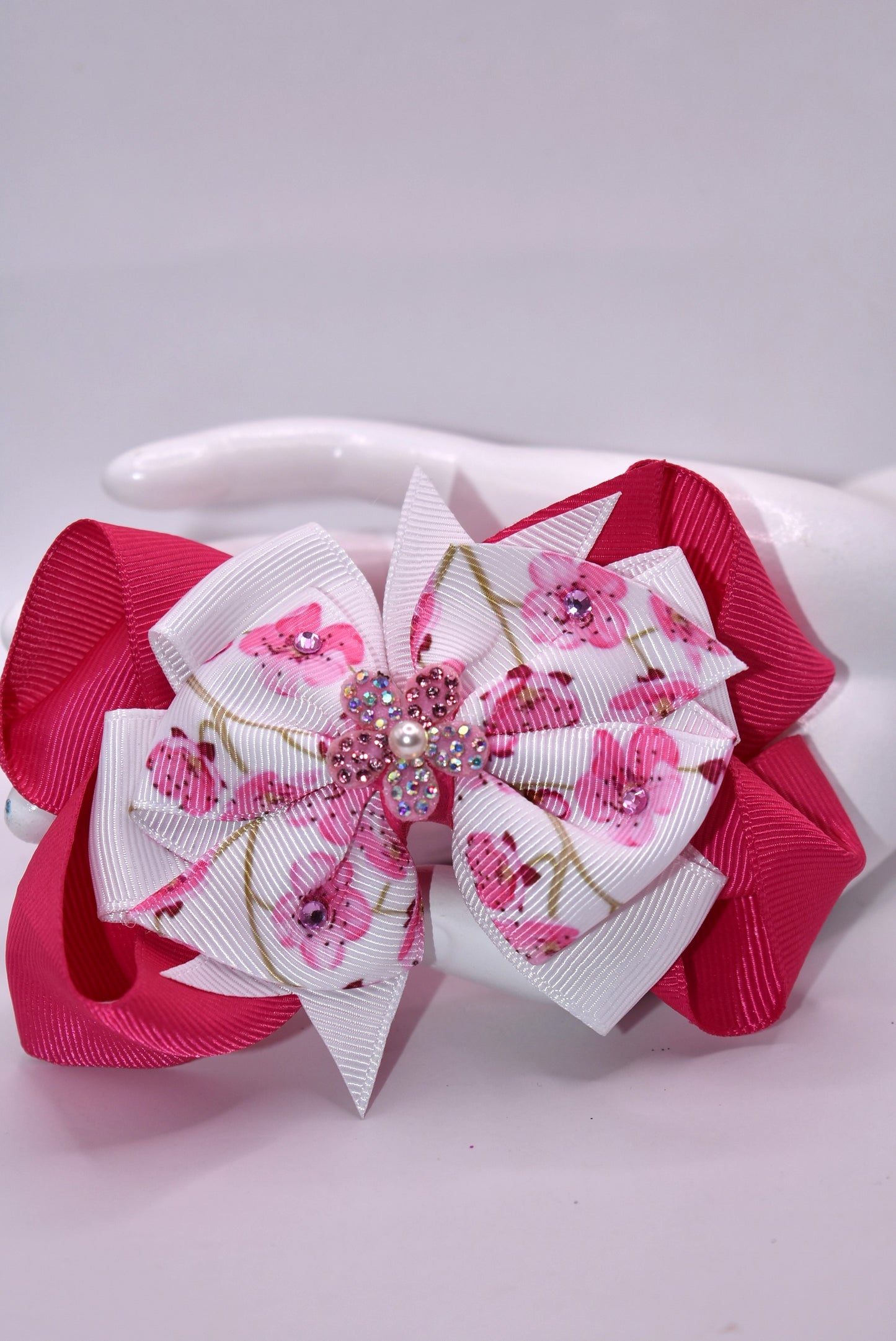 Add a pop of sparkle to your spring style with this vibrant hot pink and white floral bow! 🌸✨ Adorned with delicate crystals that catch the light and topped with a gorgeous sparkly flower accent featuring a tiny pearl, this bow brings fun and glamour to any look. 💎 The secure wrapped alligator clip keeps it perfectly in place all day long, so you can play, twirl, and shine without worry. 🎀 Perfect for adding that extra touch of joy to your spring collection! 🌷💕