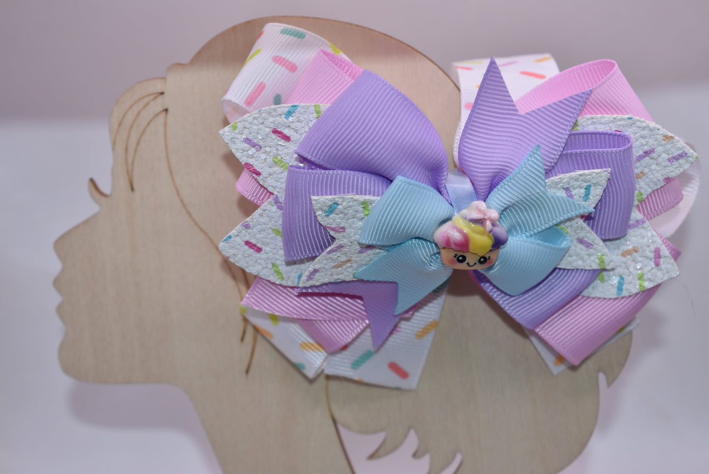 This adorably delicious sprinkle bow is pure cuteness! 🎀✨ Layered ribbon and faux leather create a textured, eye-catching design that's absolutely irresistible. A sweet little cupcake charm perches on top, adding the perfect finishing touch to this charming accessory. 🧁 The wrapped alligator clip on back ensures a secure, comfortable fit all day long. Perfect for adding a playful pop of personality to any hairstyle! 💕