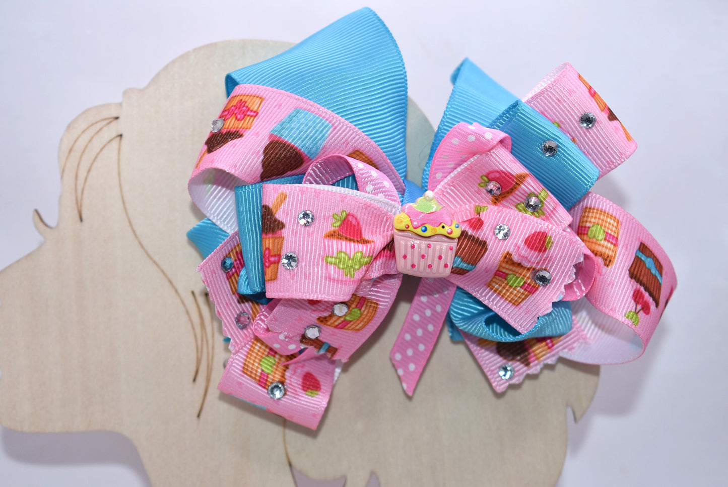 🧁 Sweet dreams come true with this adorable cupcake bow! Featuring layers of delightful cupcake-printed ribbon that stack for maximum cuteness, this accessory sparkles with dazzling crystals that catch the light beautifully. The precious little cupcake charm sits perfectly on top, adding that final touch of charm. Secured with a wrapped alligator clip, it's effortless to wear and removes easily whenever you want. Perfect for adding a sprinkle of sweetness to your day! 🎀✨