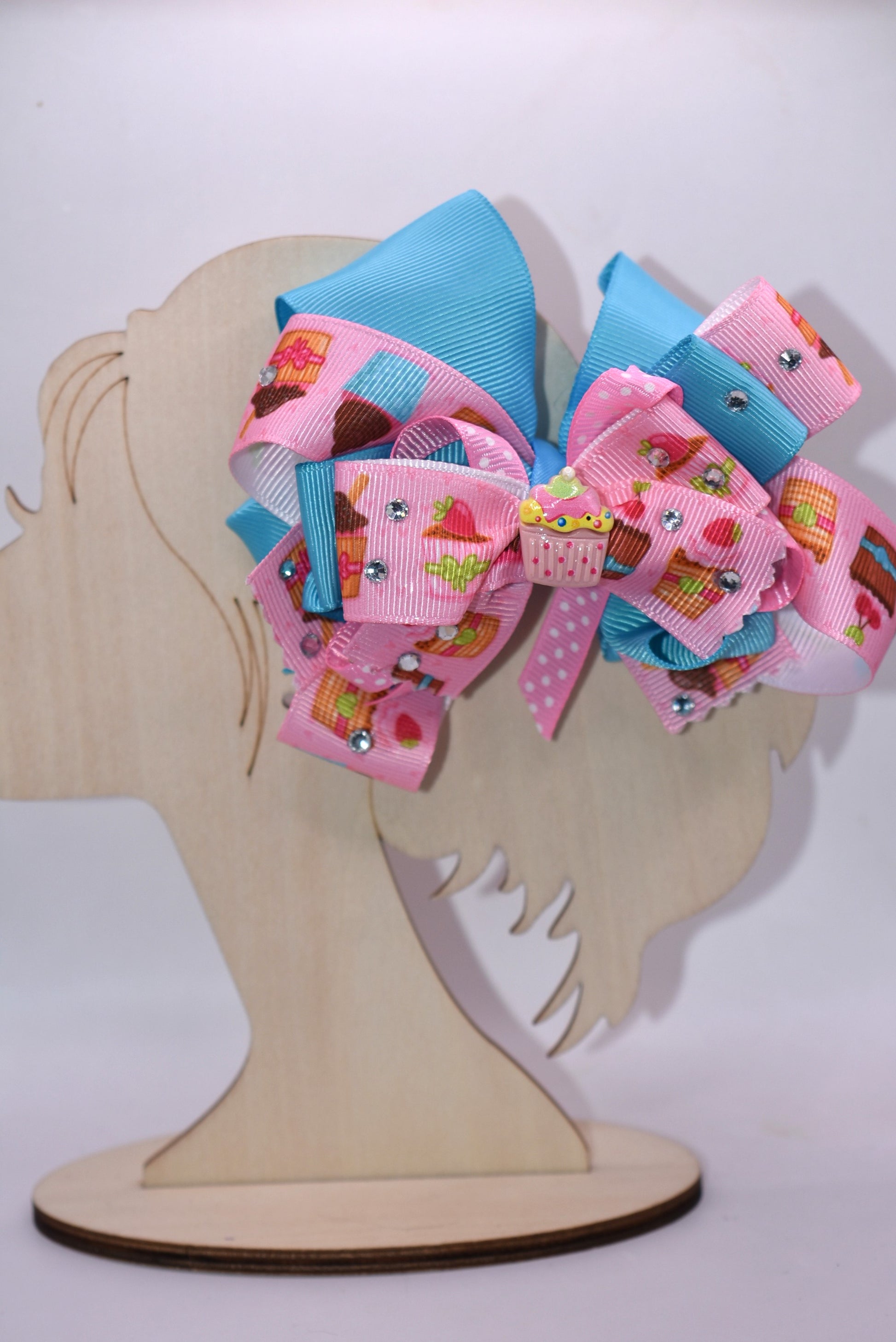 🧁 Sweet dreams come true with this adorable cupcake bow! Featuring layers of delightful cupcake-printed ribbon that stack for maximum cuteness, this accessory sparkles with dazzling crystals that catch the light beautifully. The precious little cupcake charm sits perfectly on top, adding that final touch of charm. Secured with a wrapped alligator clip, it's effortless to wear and removes easily whenever you want. Perfect for adding a sprinkle of sweetness to your day! 🎀✨