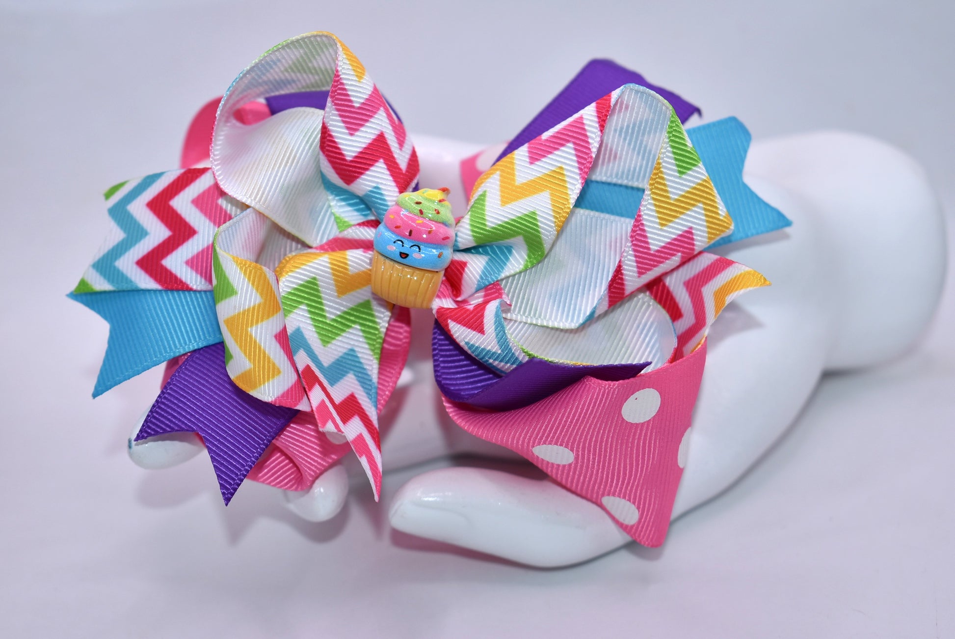 Sweeten your style with this delightful bow! 🎀✨ Featuring vibrant, layered bows adorned with ribbons in a rainbow of colors, this playful accessory brings instant charm to any look. A precious little cupcake charm perches on top, adding an extra touch of sugary sweetness. 🧁 The sturdy metal alligator clip makes styling effortless—just clip and go! Perfect for hair, bags, or anywhere you want to add a pop of fun and personality. 💕🌈