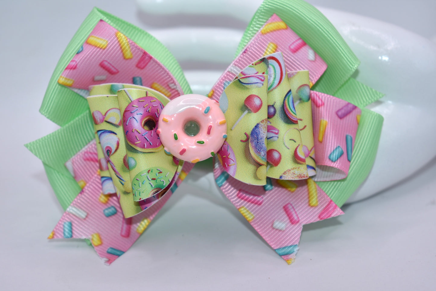 🍩 Calling all donut devotees! This adorable bow brings sweet style to your collection with its bright, cheerful design. Featuring layers of faux leather and ribbon adorned with a delightful donut motif, it's topped with the cutest pink sprinkle donut charm you've ever seen. Perfect for adding a pop of sugary sweetness to your accessories! 🎀✨