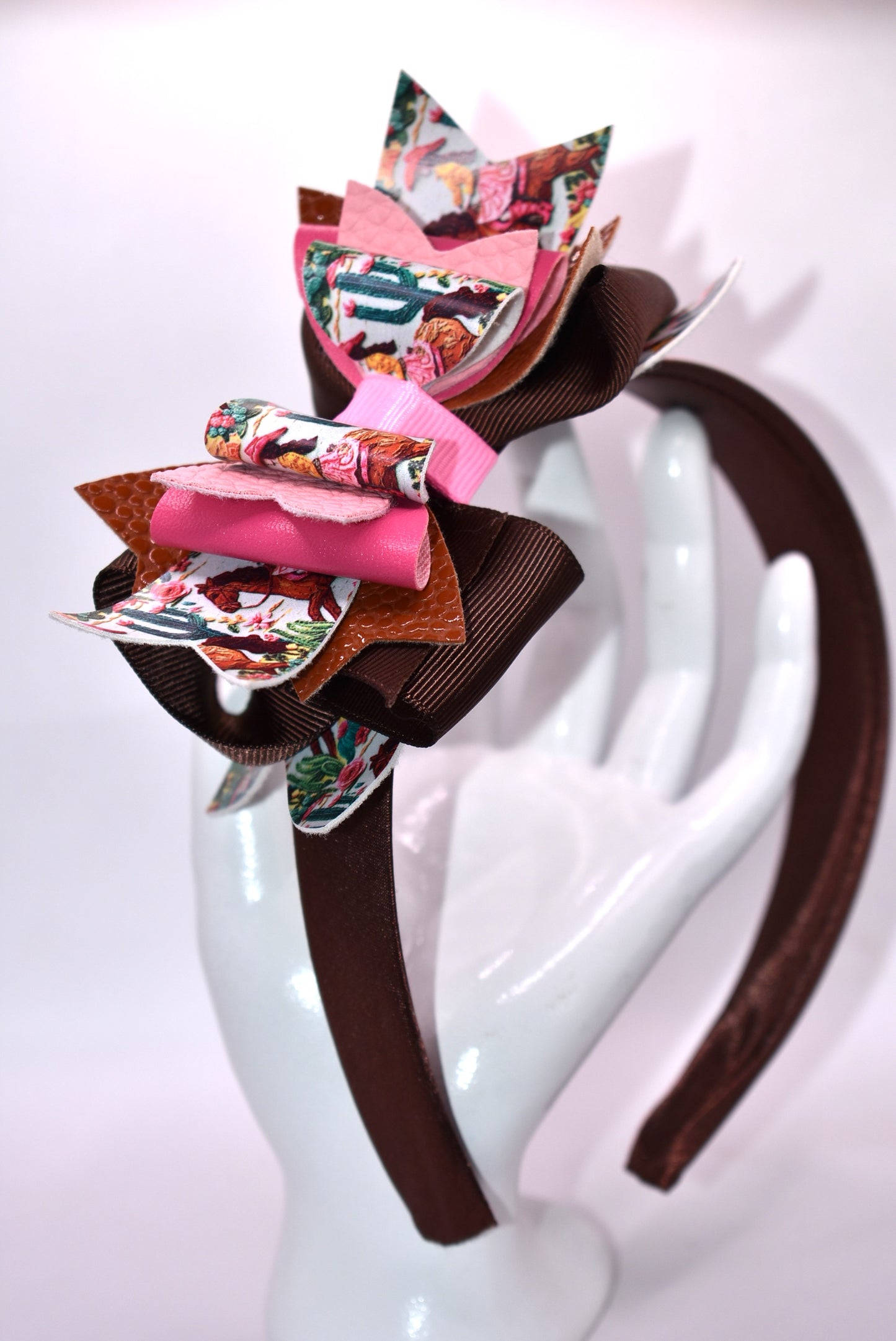Saddle up, partner! 🤠 This one-of-a-kind headband brings serious cowgirl vibes with its charming faux leather and ribbon motif in gorgeous shades of brown and pink. 🌸 The wide silk construction keeps things comfy all day long, while the flexible design moves with you—no pinching, no fussing. Whether you're channeling your inner rodeo queen or just want to add some playful Western flair to your look, this beauty delivers style with zero compromise. 💕 Yeehaw!