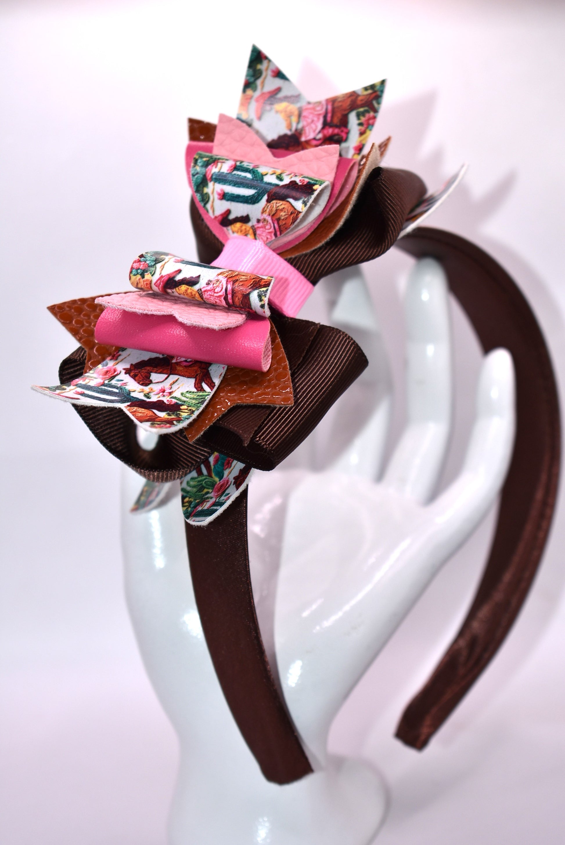 Saddle up, partner! 🤠 This one-of-a-kind headband brings serious cowgirl vibes with its charming faux leather and ribbon motif in gorgeous shades of brown and pink. 🌸 The wide silk construction keeps things comfy all day long, while the flexible design moves with you—no pinching, no fussing. Whether you're channeling your inner rodeo queen or just want to add some playful Western flair to your look, this beauty delivers style with zero compromise. 💕 Yeehaw!