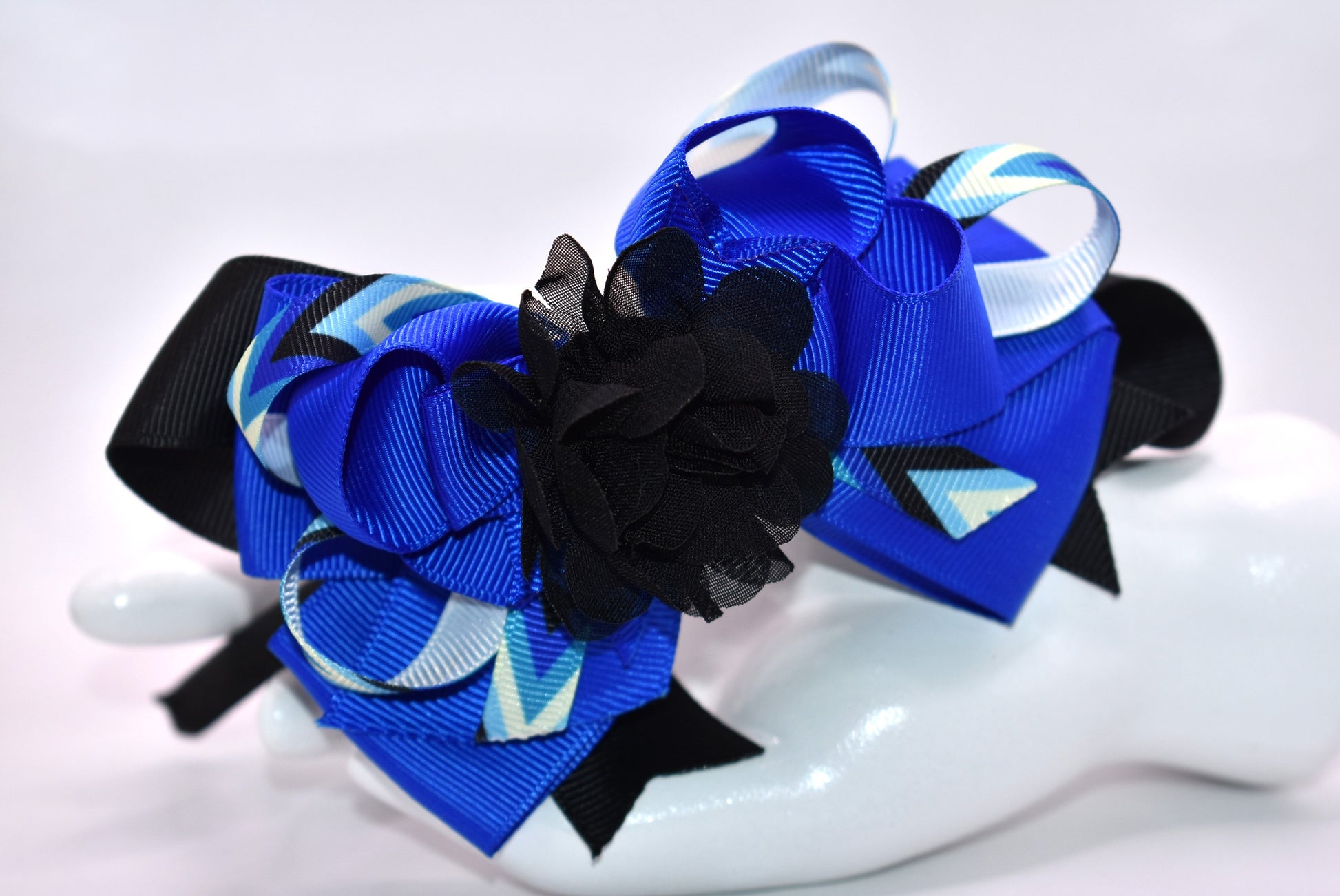 ✨ Elevate your look with this stunning blue and black headband from Nana's Collection! Crafted from silky satin for all-day comfort, this thin, lightweight design features beautifully layered ribbons that add dimension and style. Topped with an elegant black chiffon flower, it's the perfect finishing touch for any outfit—from casual days to special occasions. 🎀 Whether you're dressing up or keeping it simple, this headpiece brings that extra touch of pretty to your ensemble. 💙