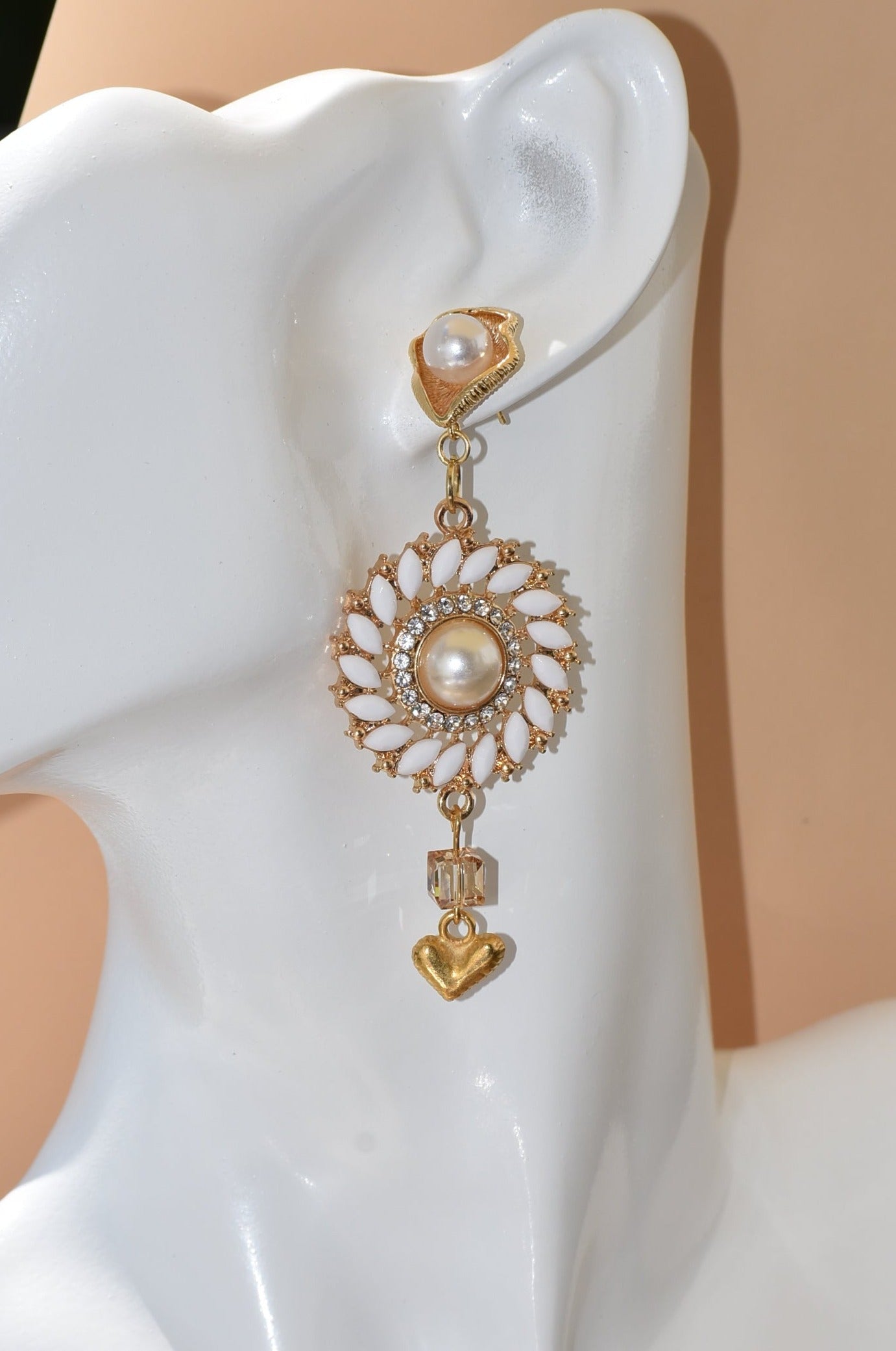 Our Wedding Collection 18 earrings feature bold gold colors and an unusual pearl post, bordered with white marquise beading and white crystals. A small gold heart hangs from the bottom, making a huge statement on the ear. Perfect for any special occasion.