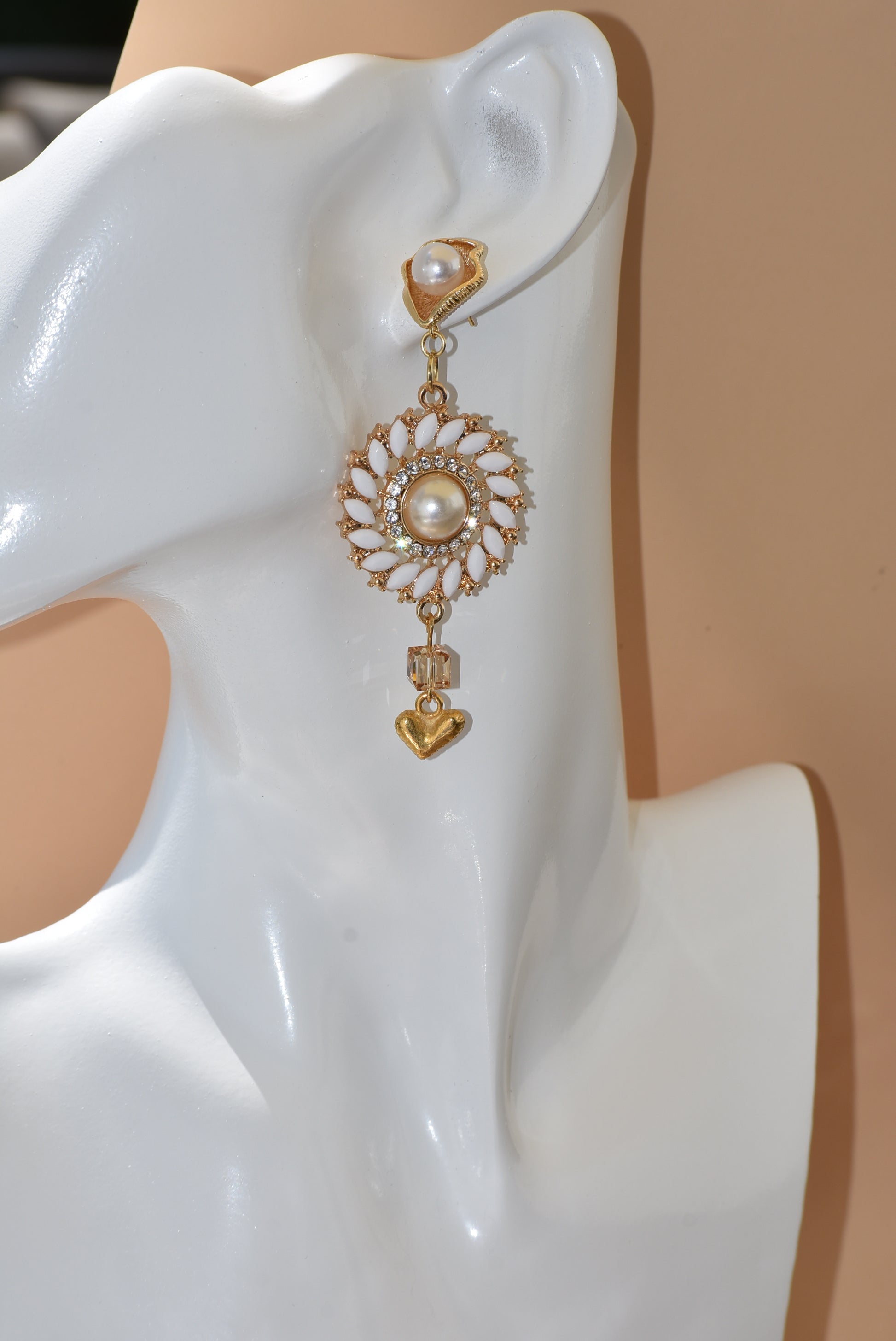 Our Wedding Collection 18 earrings feature bold gold colors and an unusual pearl post, bordered with white marquise beading and white crystals. A small gold heart hangs from the bottom, making a huge statement on the ear. Perfect for any special occasion.