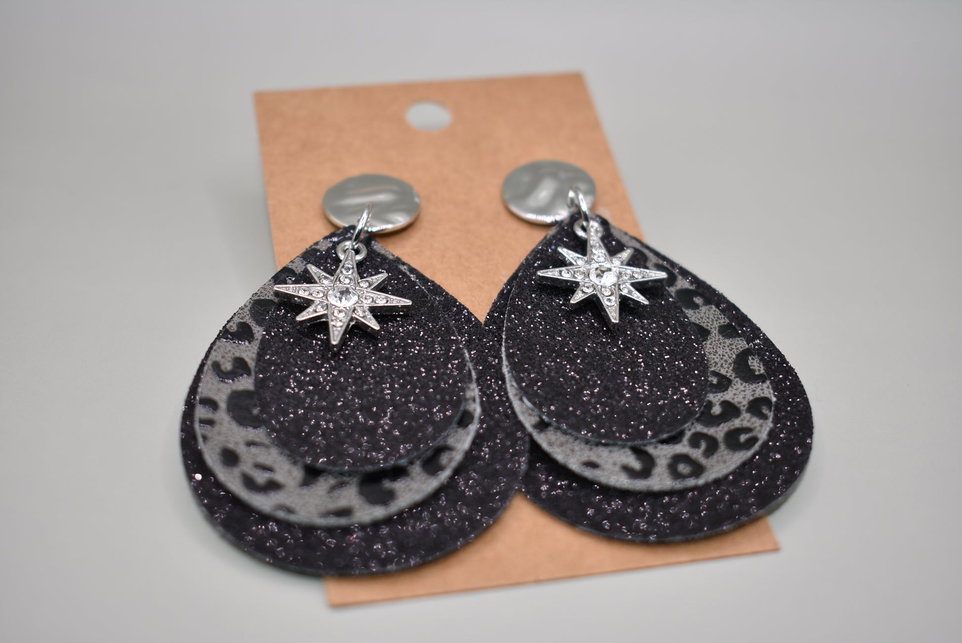 Black glitter teardrops hold a center leopard print in black and gray.  A pretty crystal star charm hangs from the top of these silver post earrings.  