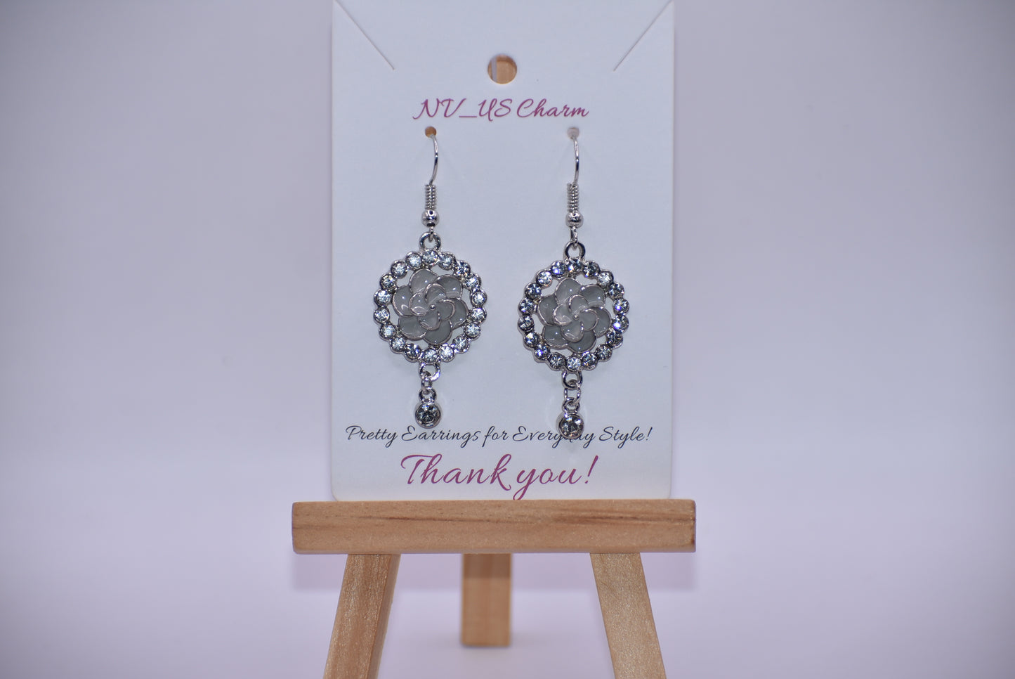 These Gray Collection 9 earrings provide a unique and sophisticated look. Featuring a pretty gray flower surrounded by crystals and a small crystal hanging, these silver hook earrings will add sparkle and elegance to any outfit. With intricate details and luxurious design, these earrings are a must-have addition to any jewelry collection.