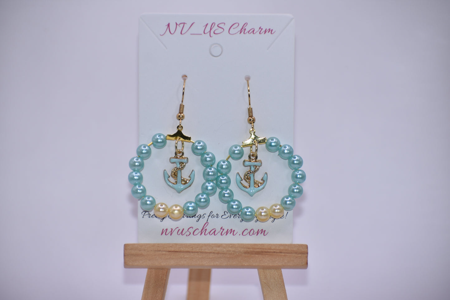 Our Nautical Collection 9 earrings feature aqua pearls with an aqua anchor charm in the center, all accented with a gold hooks. With their classic, elegant design, these earrings are sure to make a stunning addition to any look.