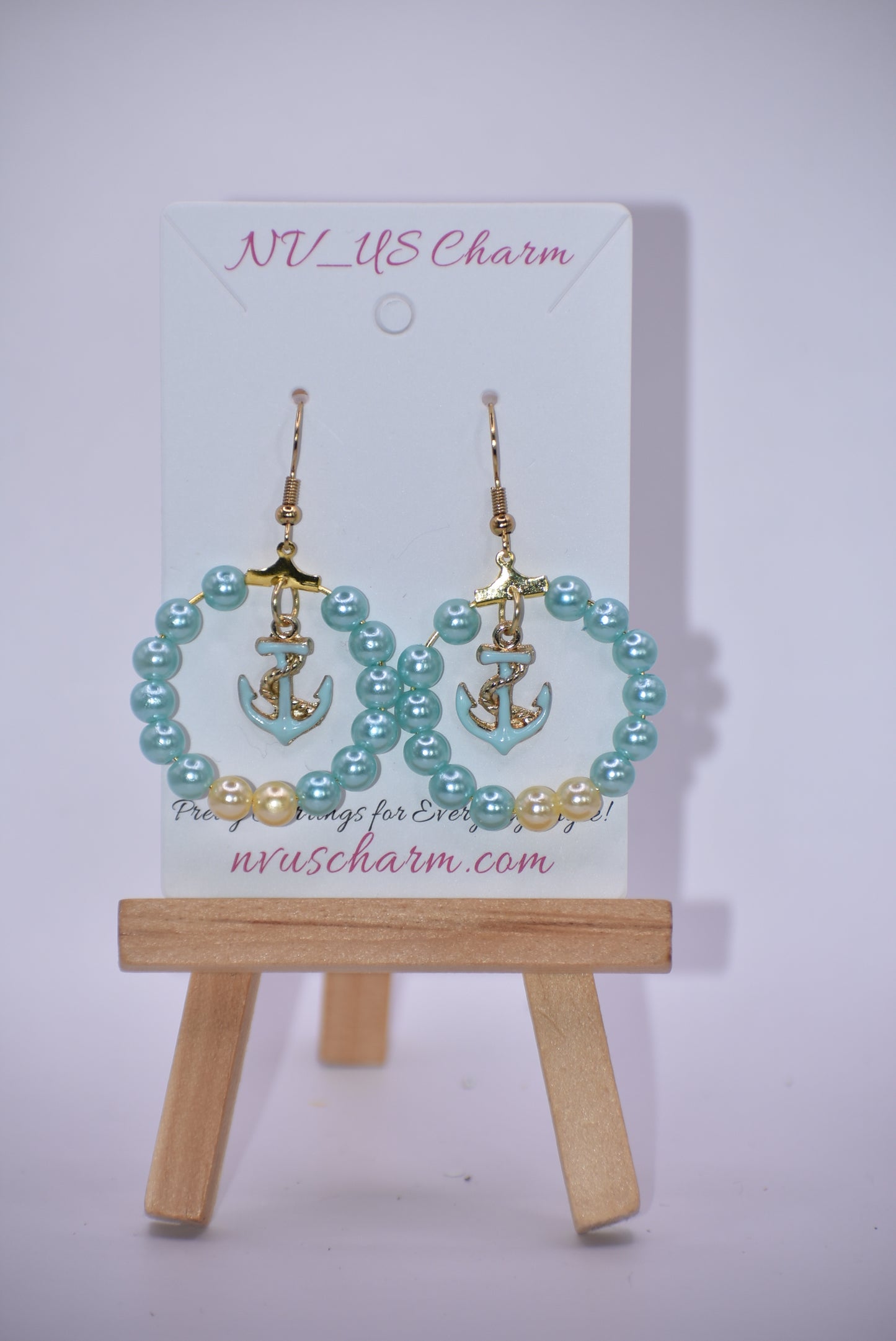 Our Nautical Collection 9 earrings feature aqua pearls with an aqua anchor charm in the center, all accented with a gold hooks. With their classic, elegant design, these earrings are sure to make a stunning addition to any look.